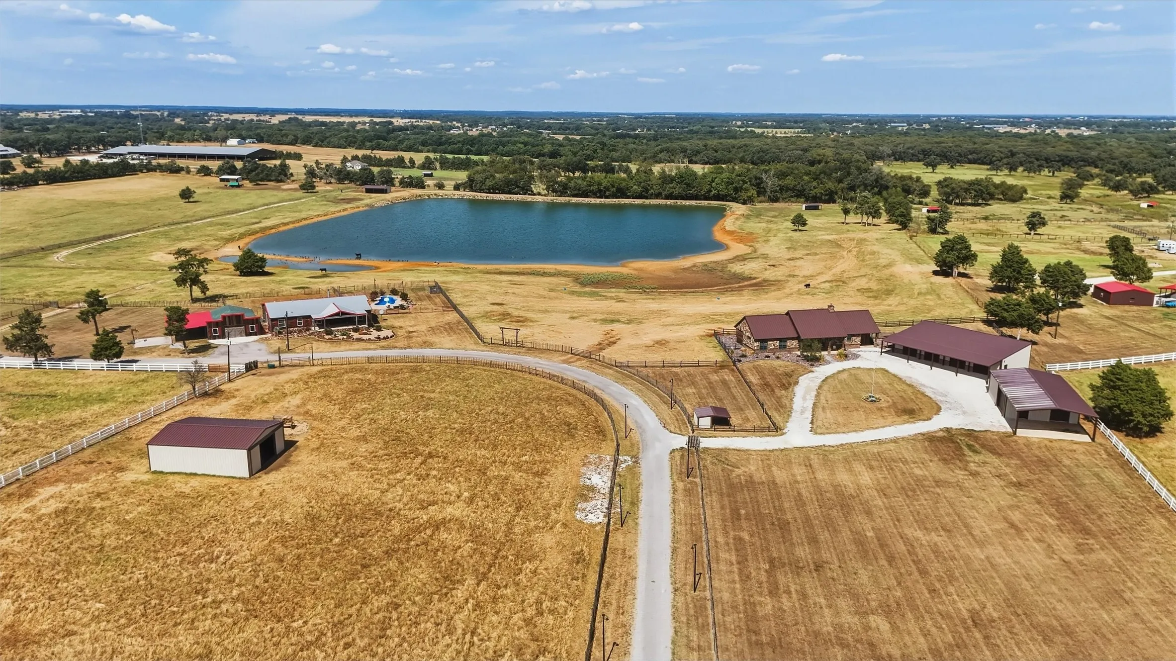 Aerial view of the custom home (upper right) and triple-wide mobile home (behind driveway - in front of pond.