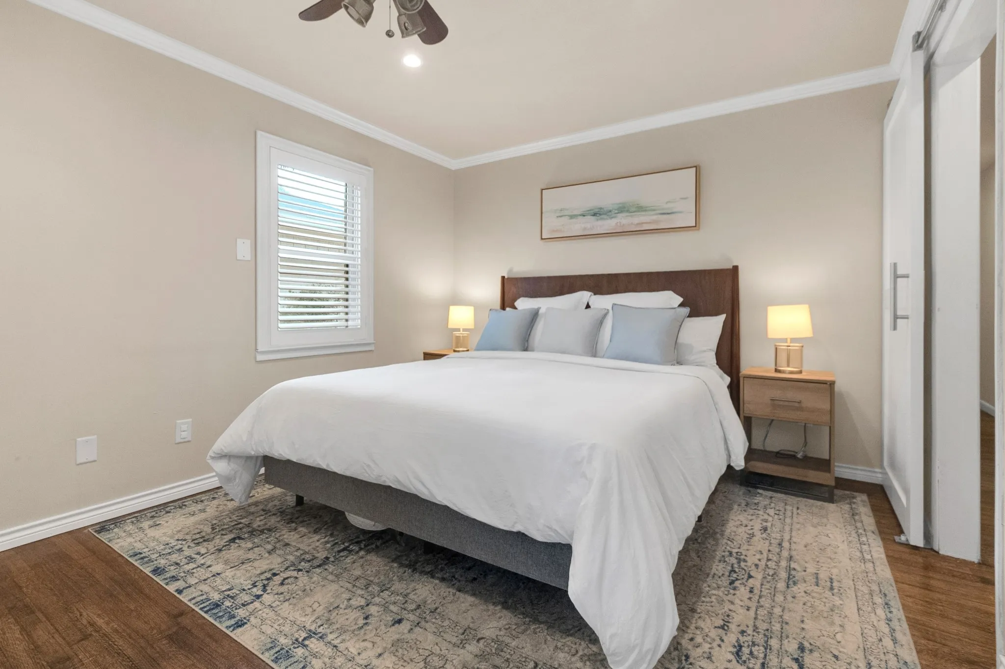 Bedroom featuring wood-finish flooring, crown molding, and a ceiling fan with integrated lighting