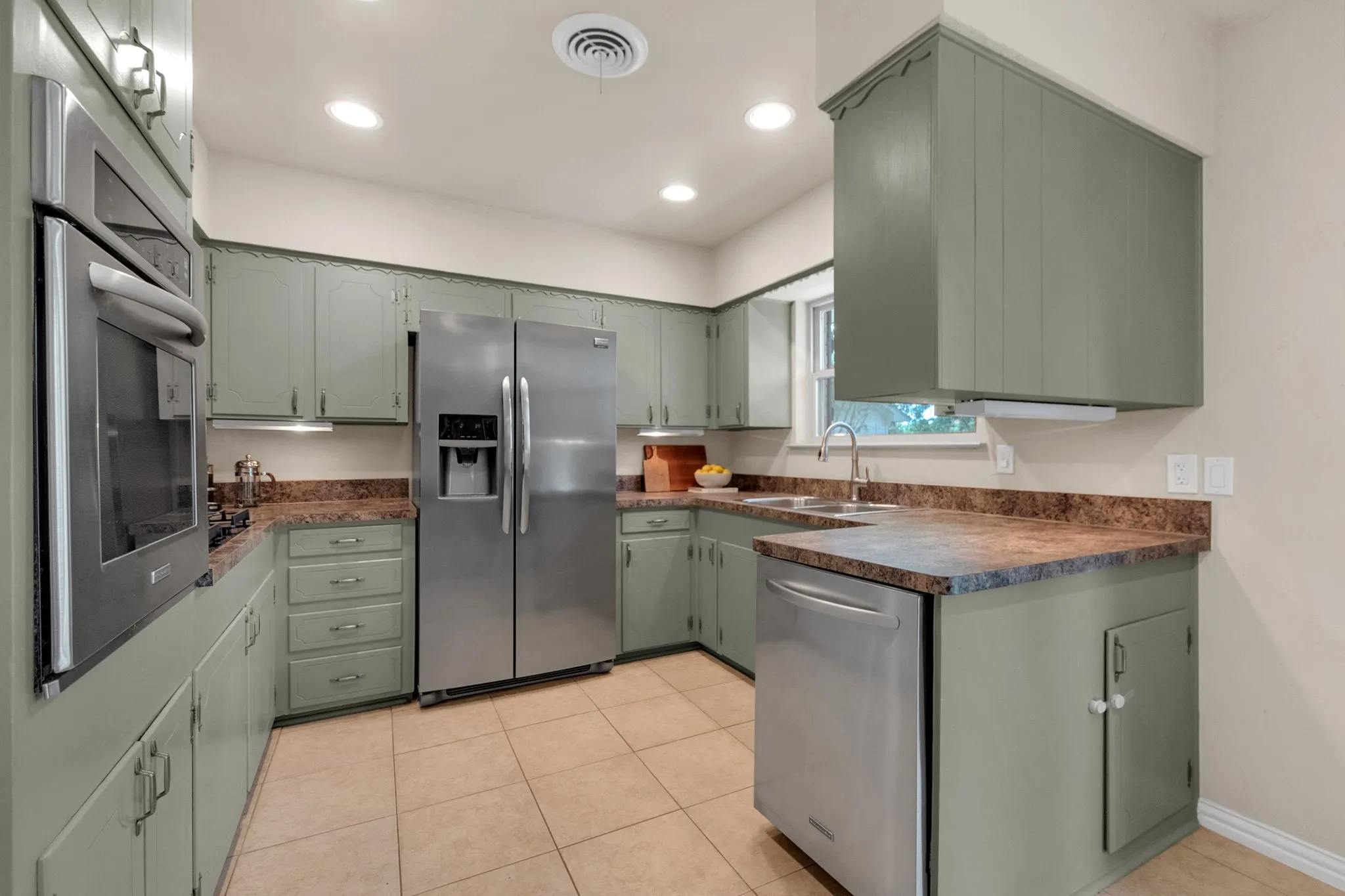U-shaped kitchen featuring sage green cabinetry, a stainless steel side-by-side refrigerator, and stone-finish countertops