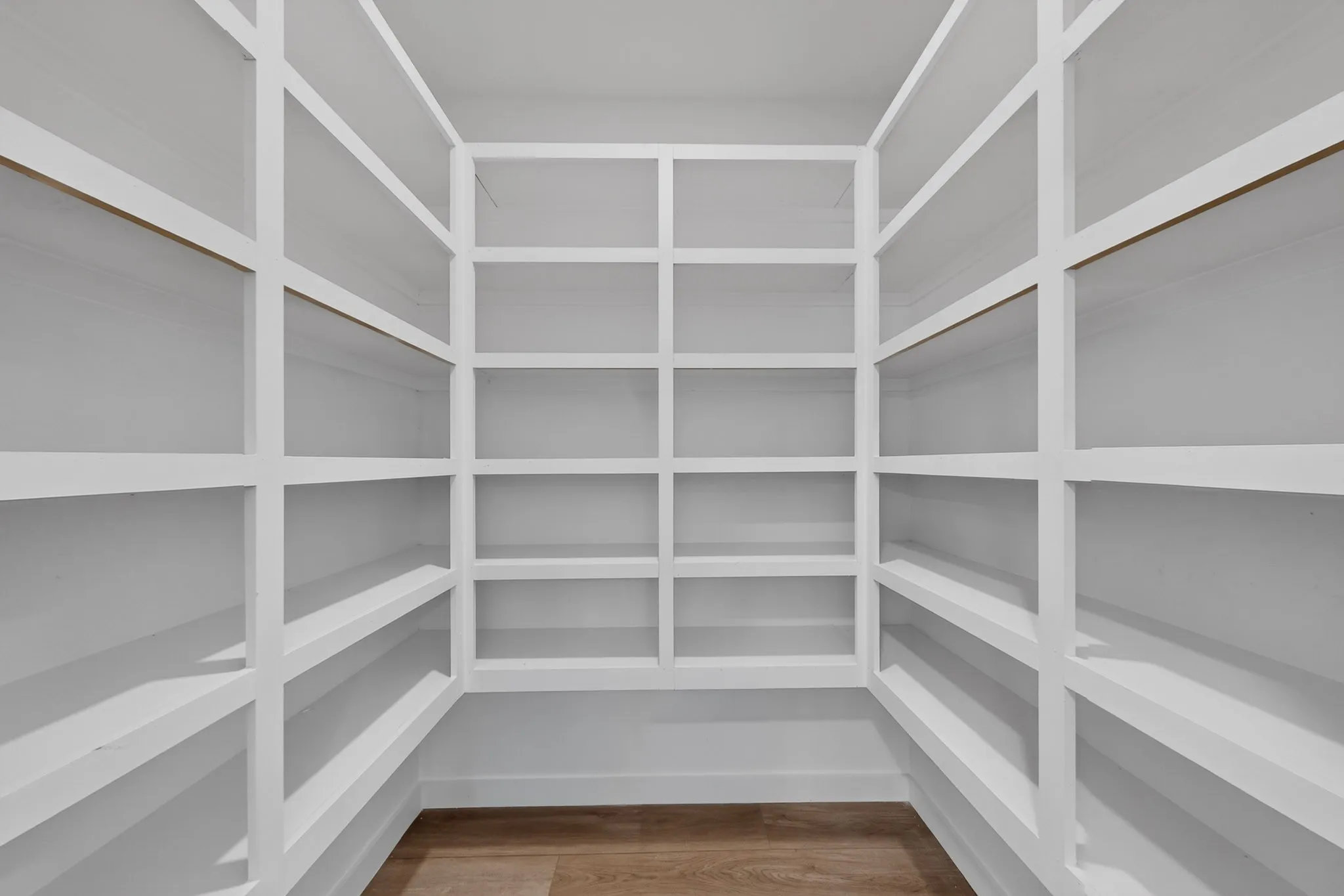 Built-in shelving with white finish, extensive storage capacity, and wood-finish flooring
