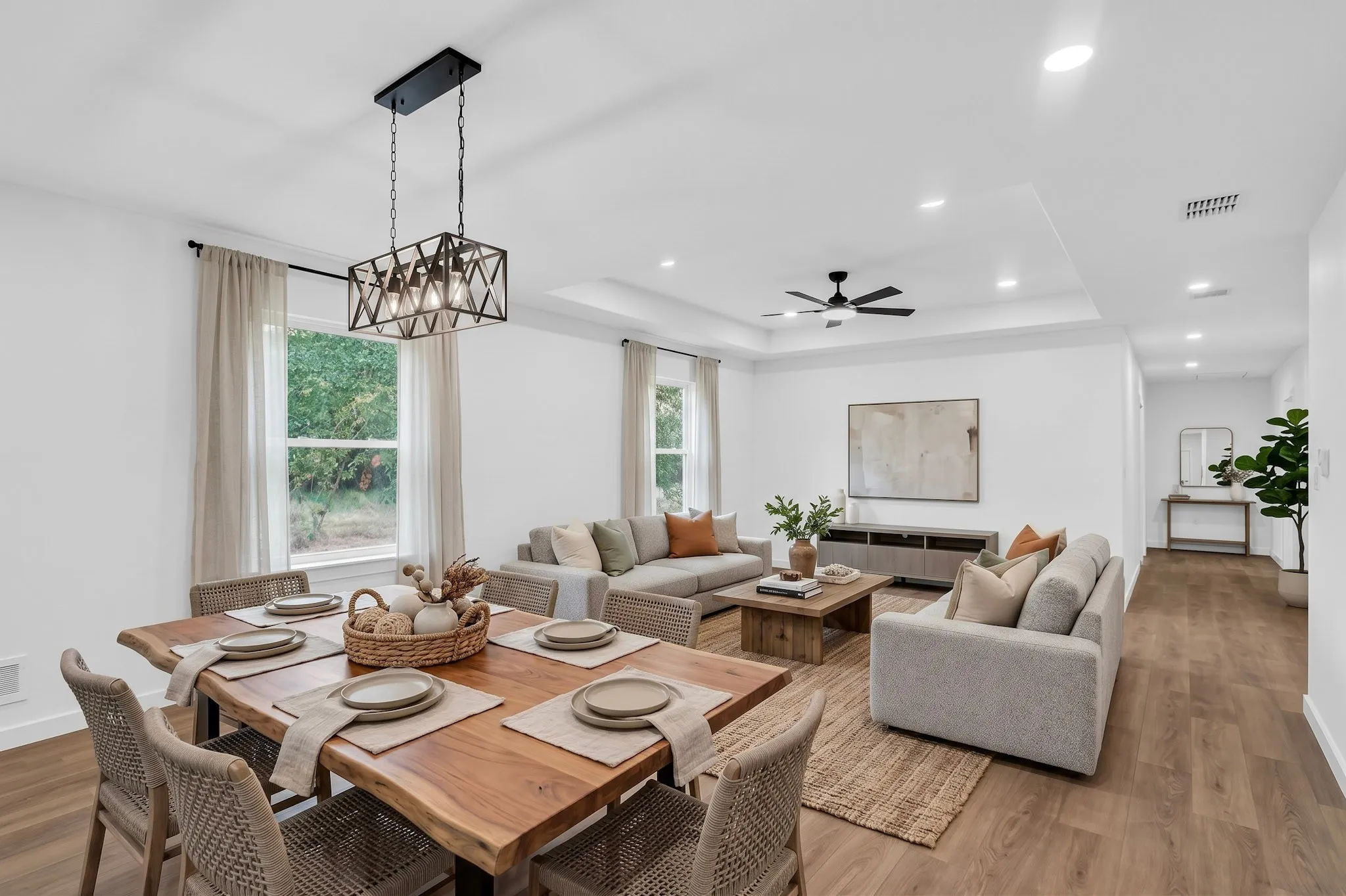 Open-concept living space with wood-finish flooring, a tray ceiling, recessed lighting, and a modern ceiling fan