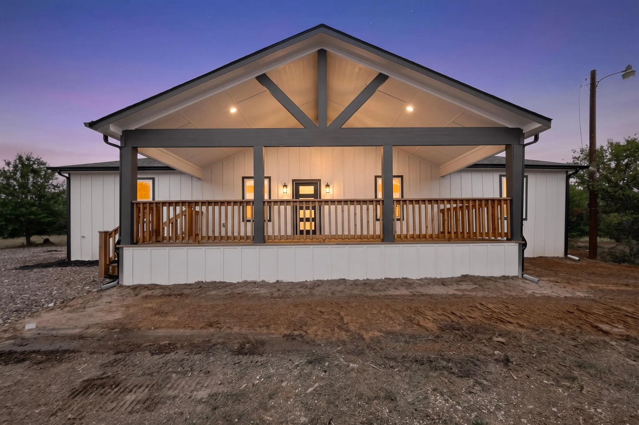 Covered porch with exposed wood trusses, wood-finish railing, and board-and-batten siding