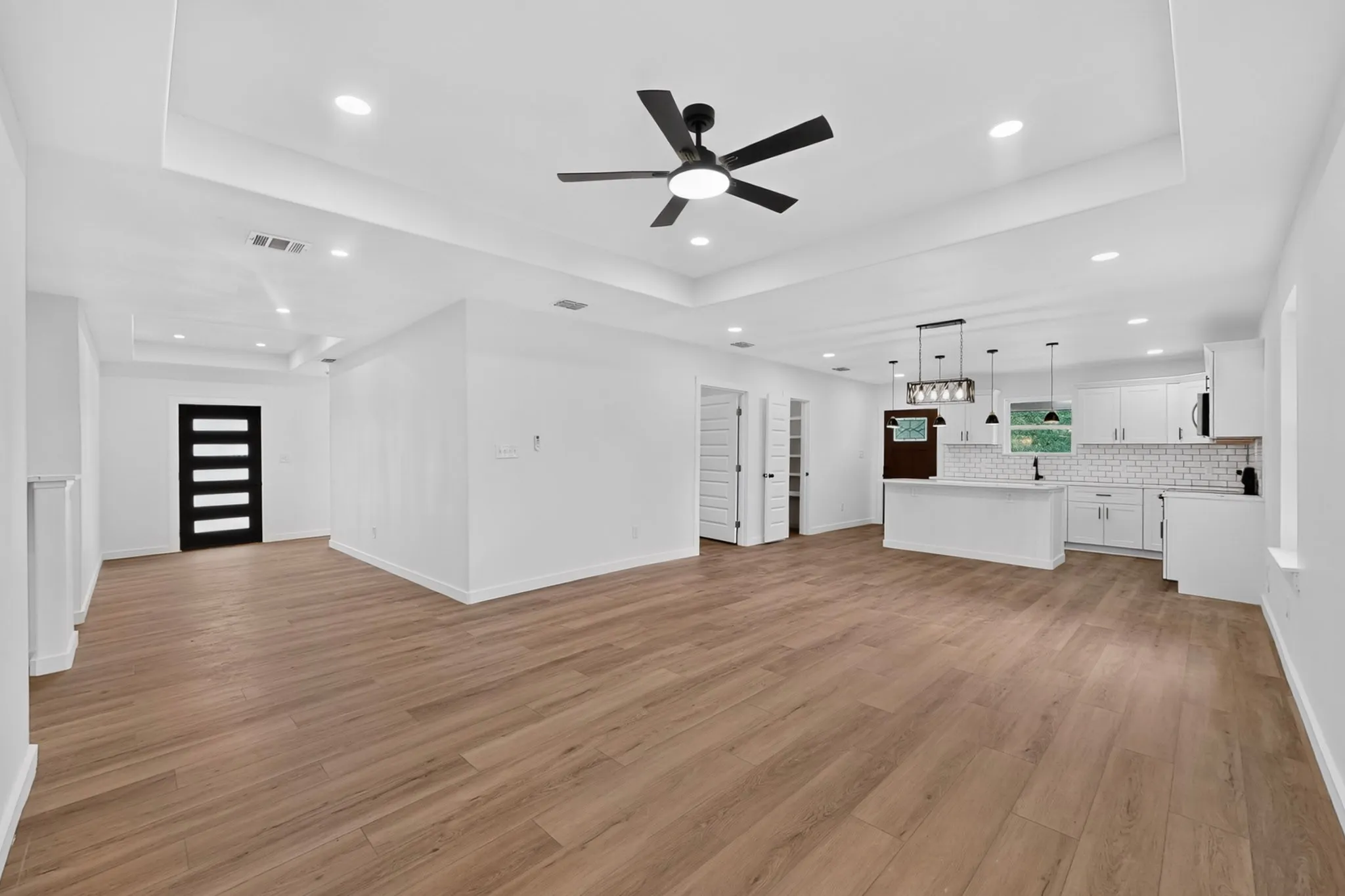 Expansive room with wood-finish flooring and tray ceilings