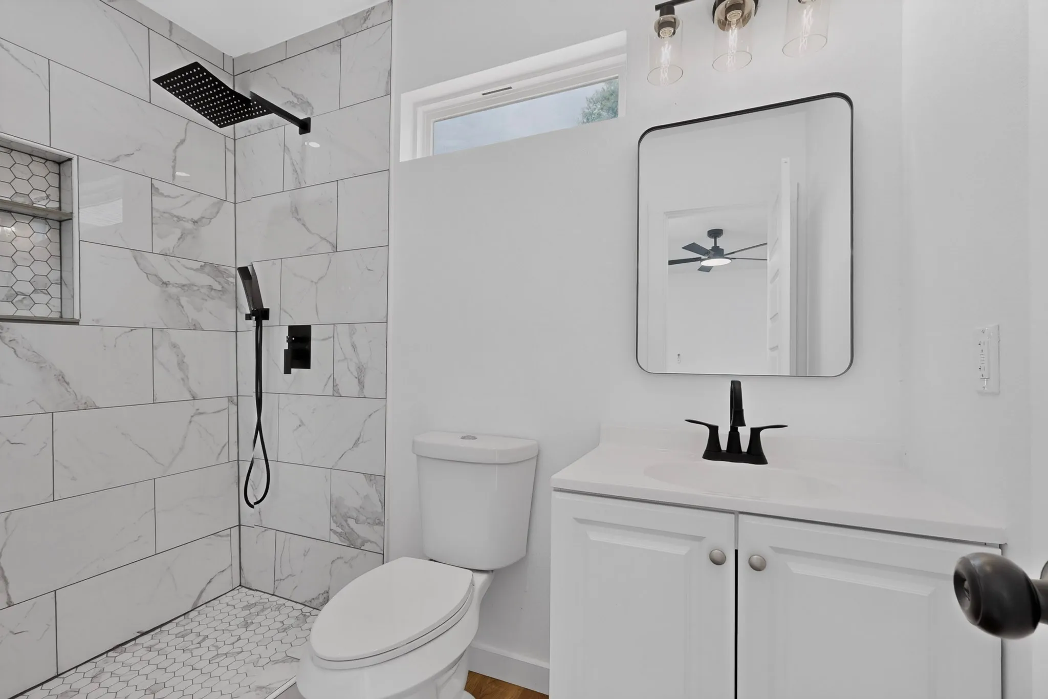Shower with large-format tile, hexagonal mosaic floor, and matte black fixtures