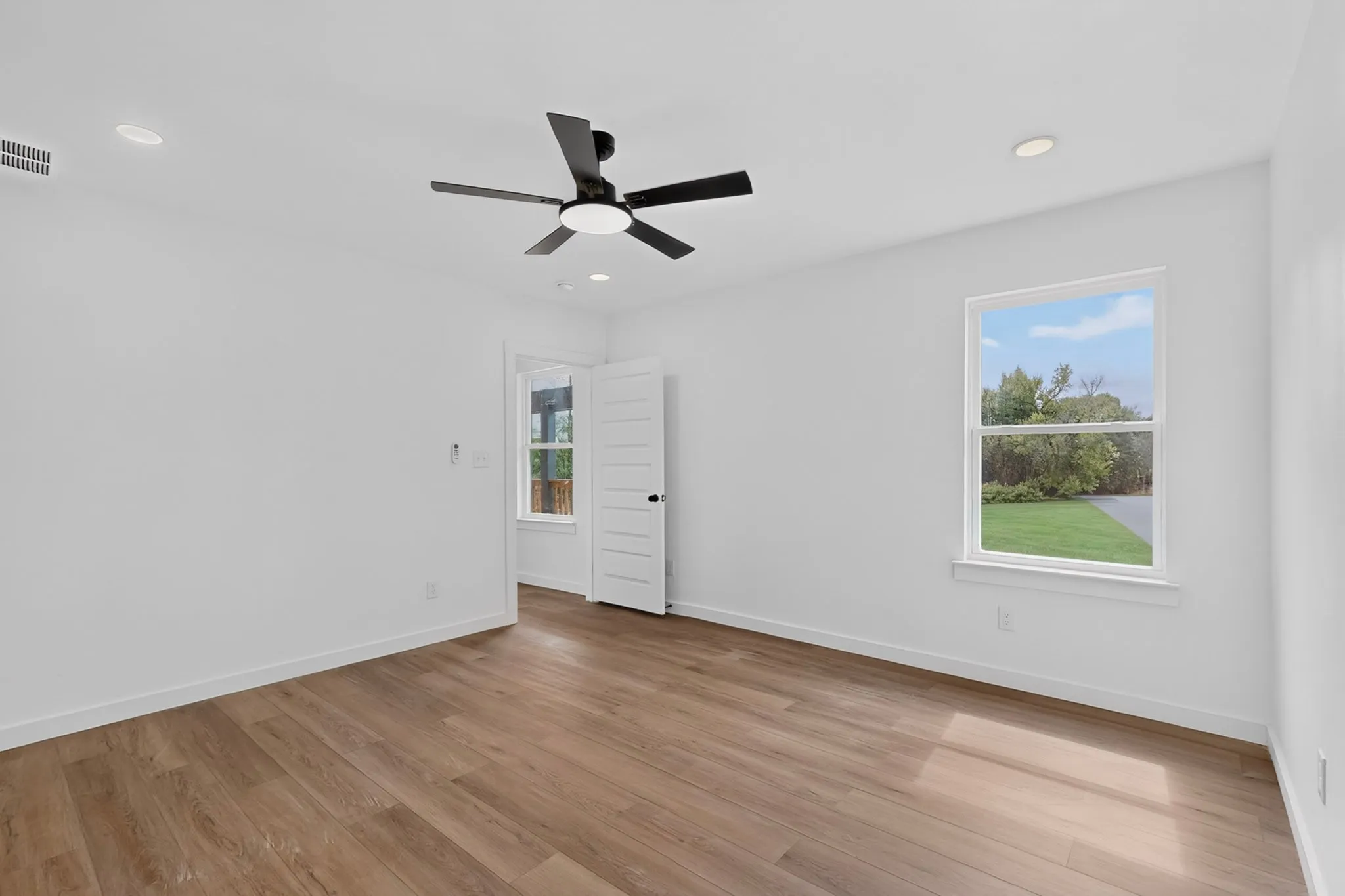 Wood-finish flooring, ceiling fan, recessed lighting, and white paneled interior doors