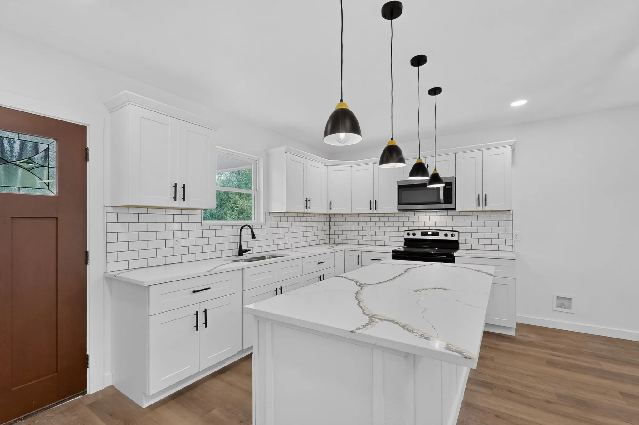 Modern kitchen featuring white cabinetry, subway tile backsplash, a center island with a stone countertop, a black kitchen range, and wood-finish flooring