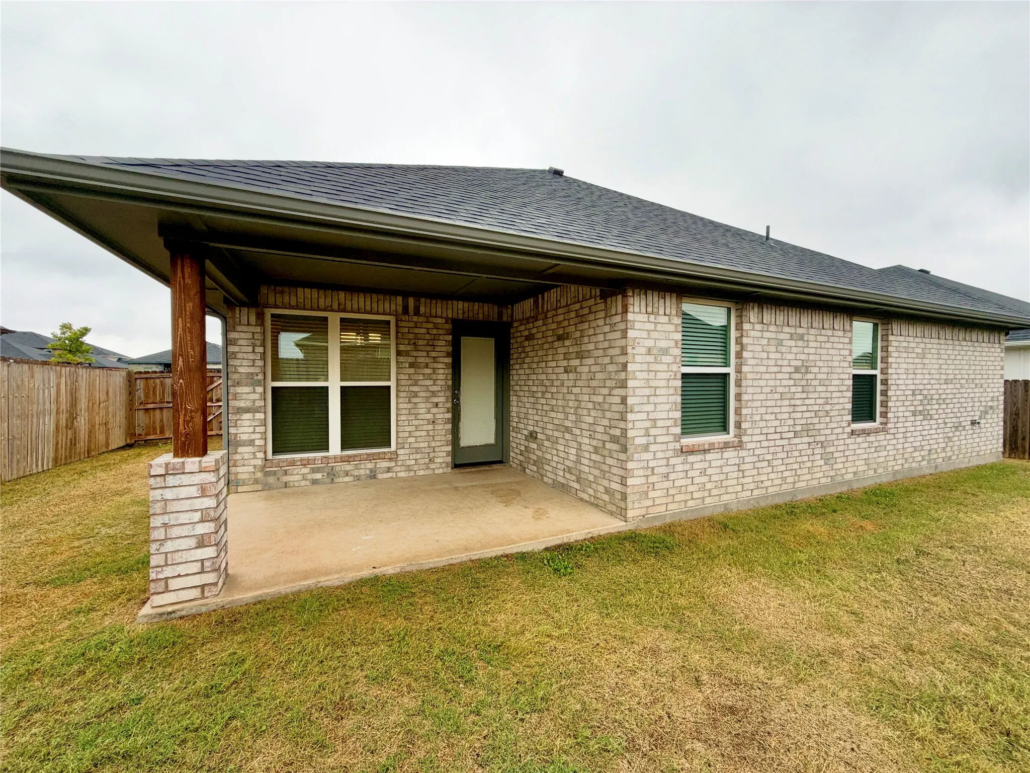 Exterior brick facade with a covered patio and concrete flooring