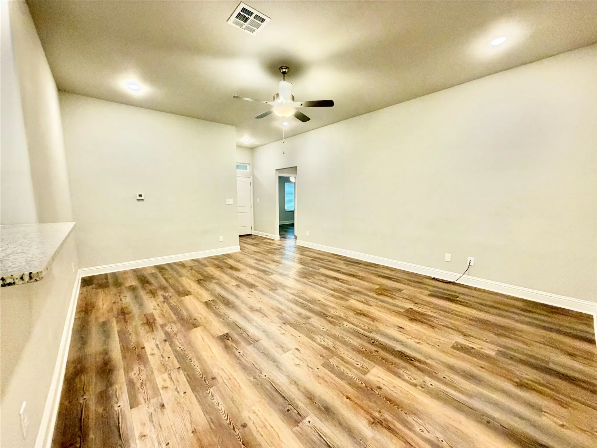 Spacious room featuring wood-finish flooring, recessed lighting, a ceiling fan, and a built-in half-wall with a stone-finish countertop