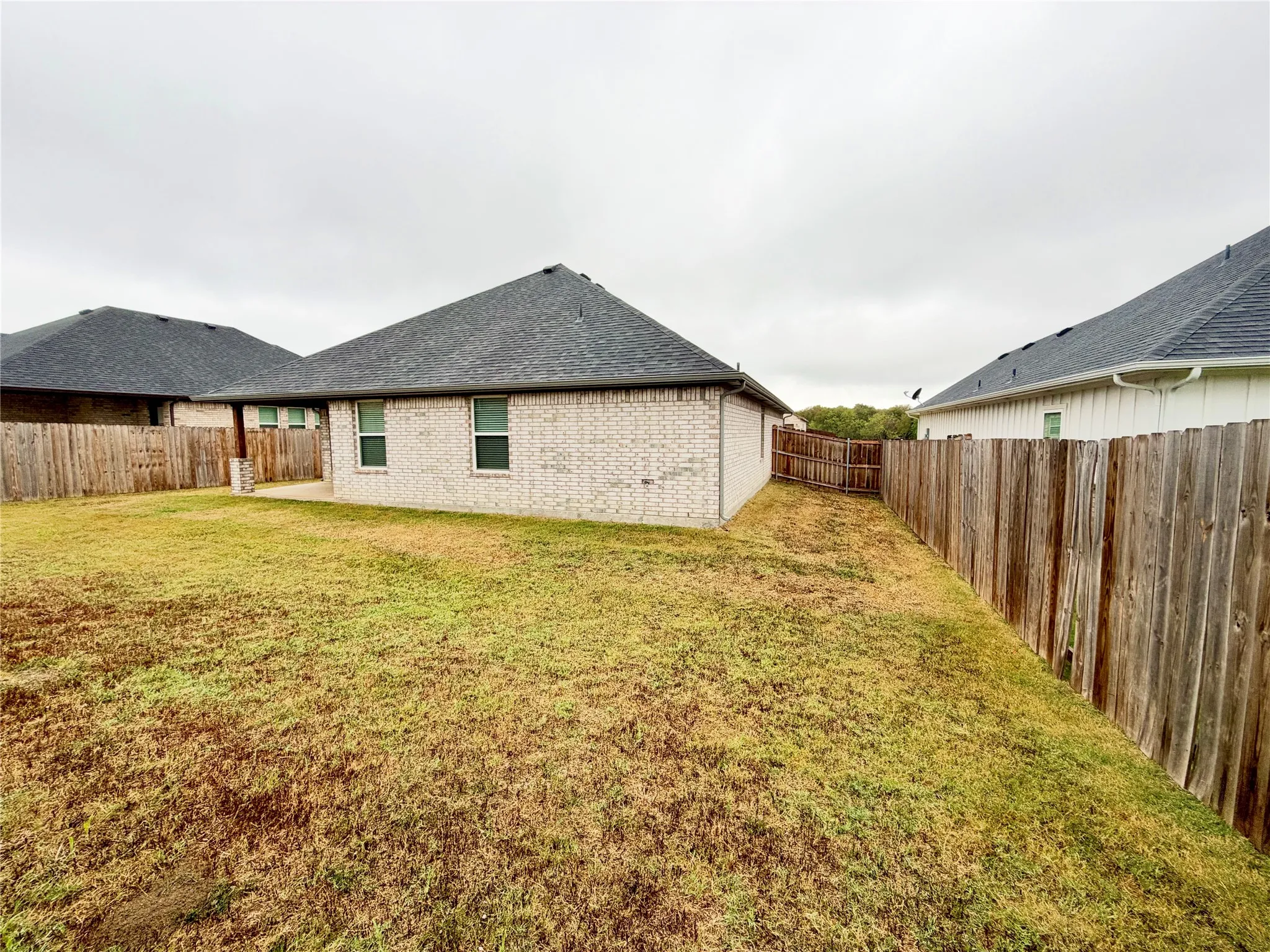Fenced backyard featuring a brick exterior and a concrete patio