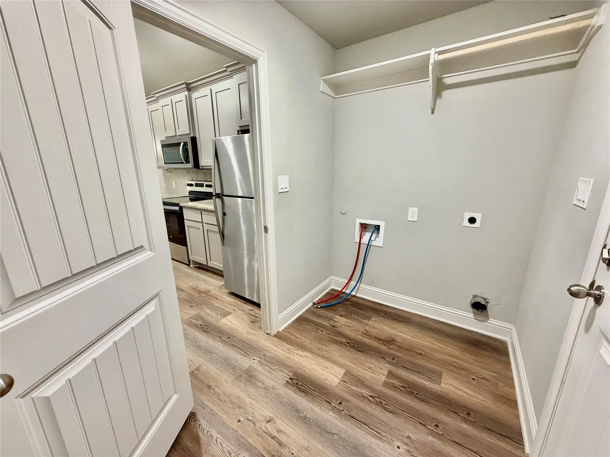 Utility room with wood-finish flooring, built-in shelving, and a panel door