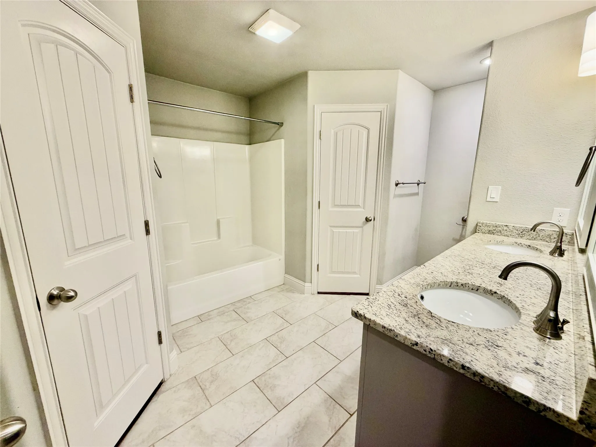 Double vanity with granite countertops, dual undermount sinks, and bronze-finish faucets