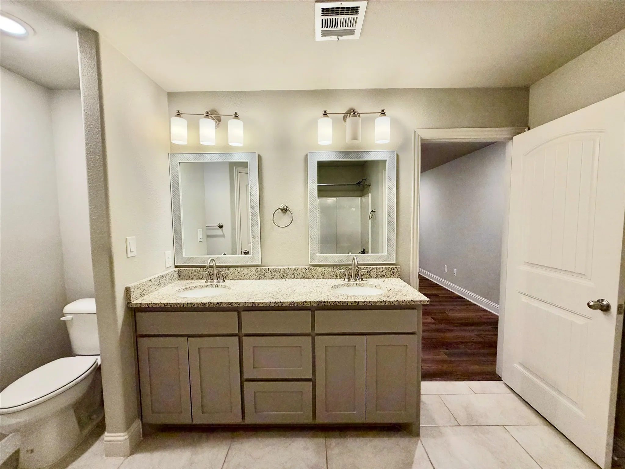 Dual vanity with granite-style countertop, undermount sinks, and brushed nickel fixtures