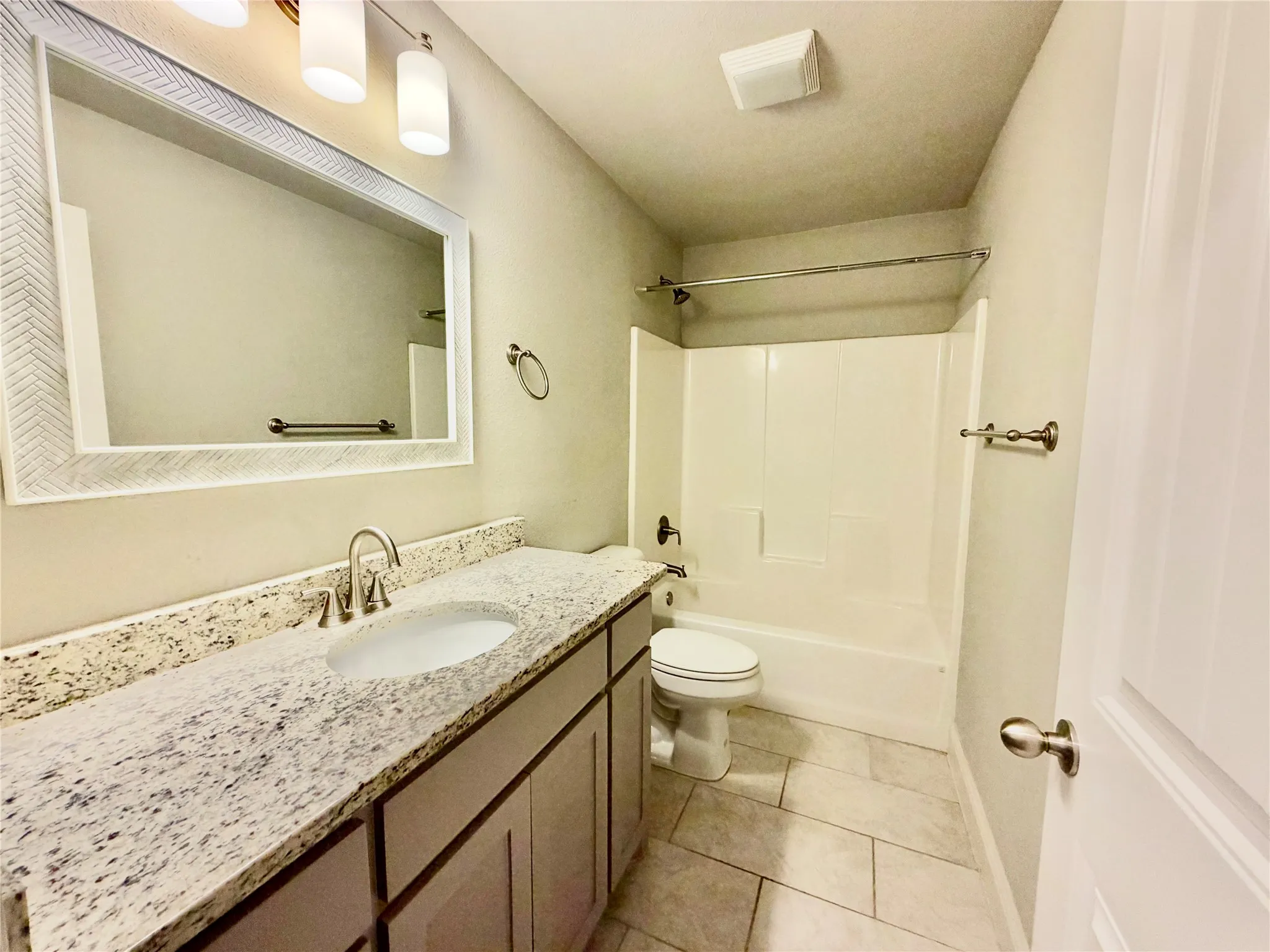 Vanity with an integrated sink, polished chrome faucet, and stone countertop