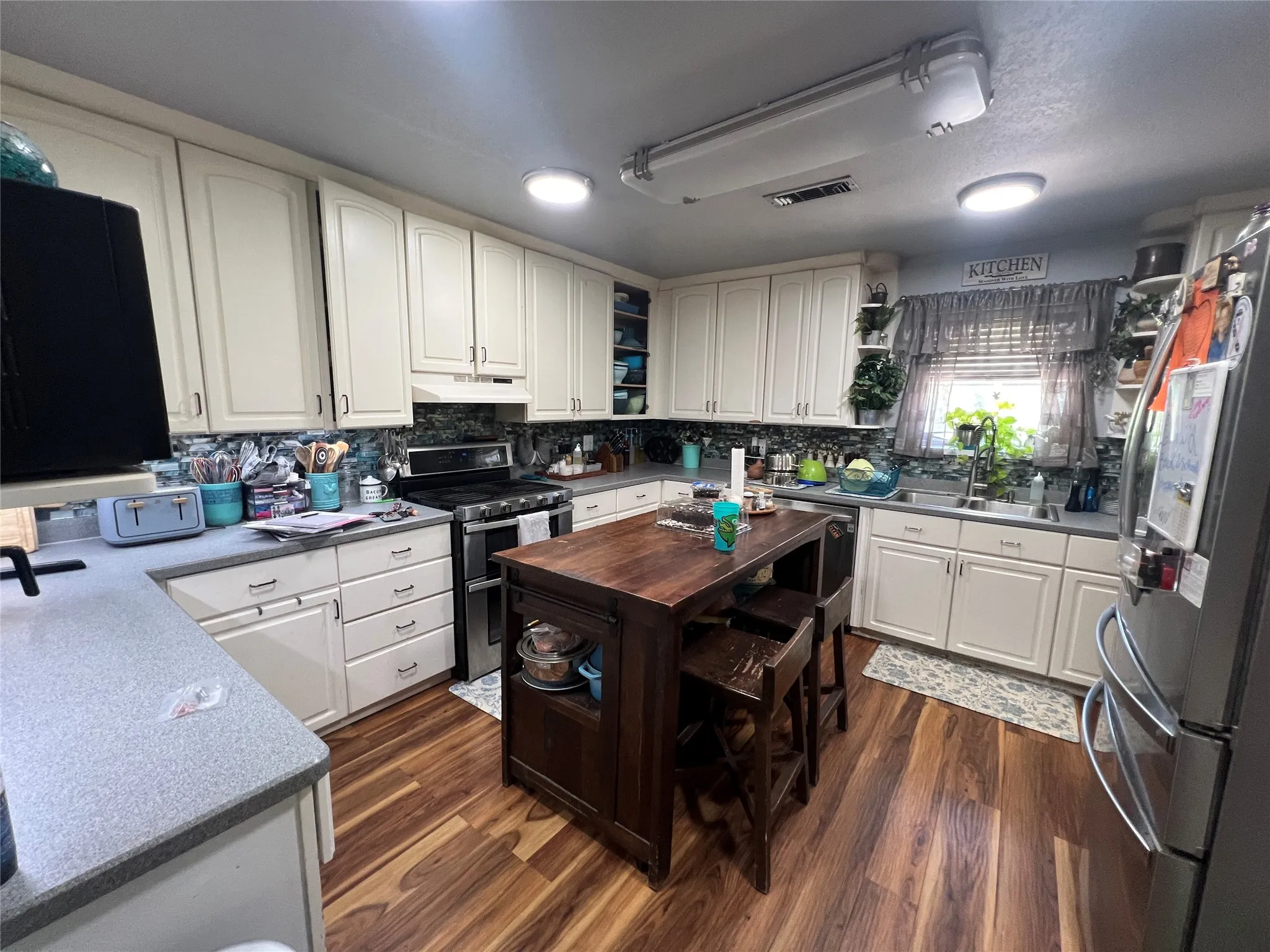 Kitchen featuring wood-finish flooring, white cabinetry, gray countertops, and a mosaic tile backsplash