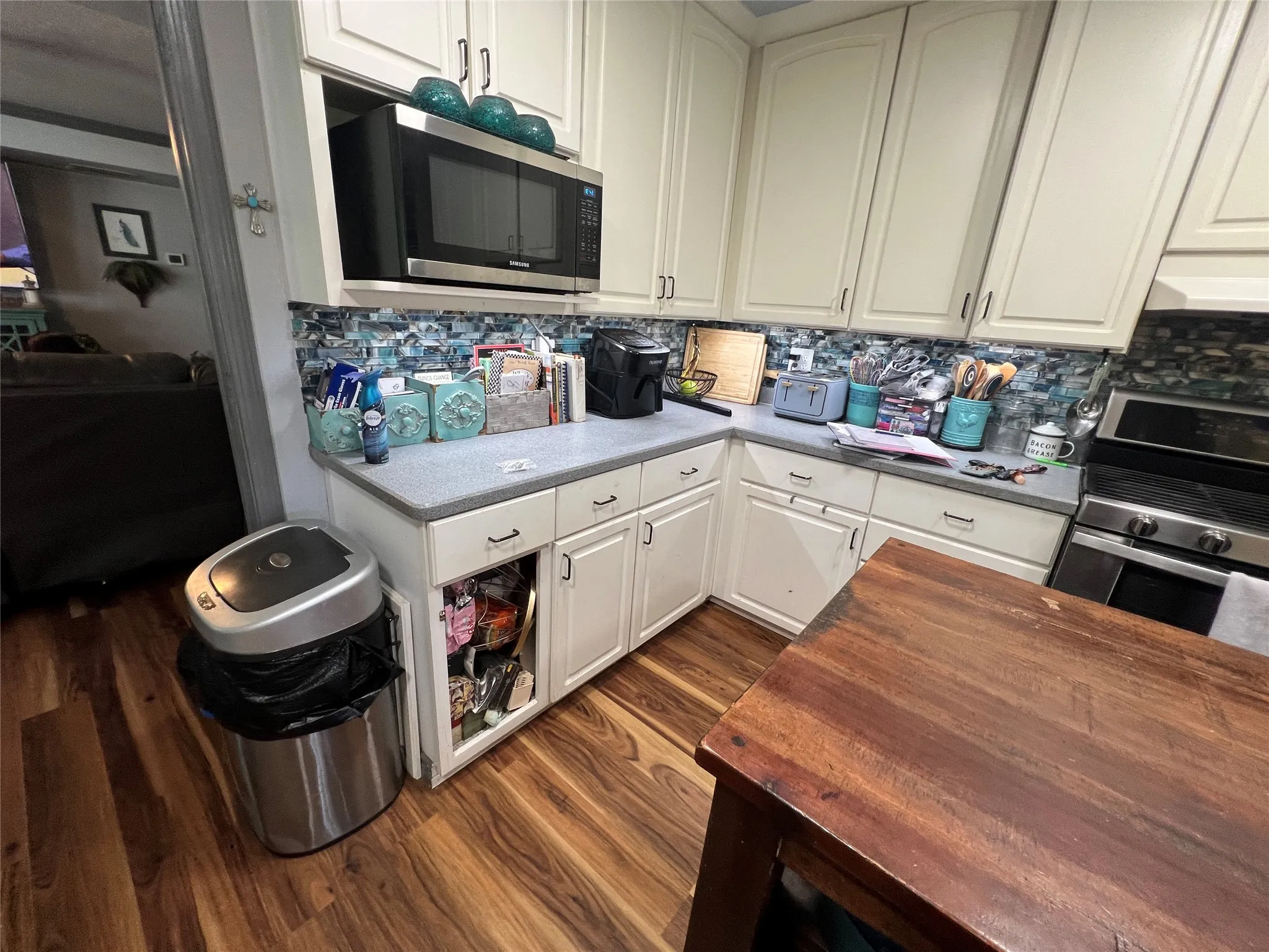 Kitchen featuring white upper and lower cabinetry, grey countertops, wood-finish flooring, and a stainless steel oven range