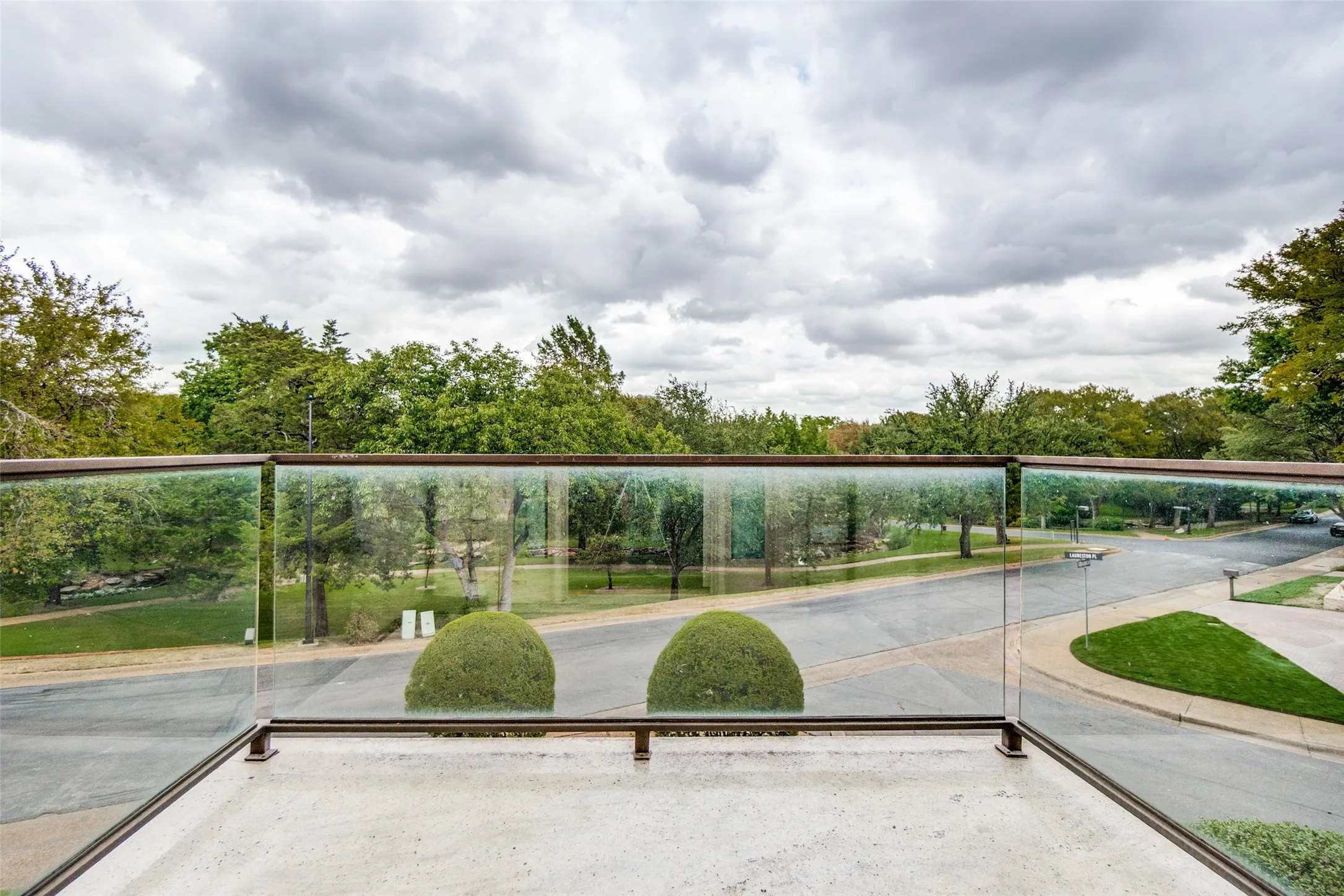 View of greenbelt from office balcony with a glass railing and metal frame