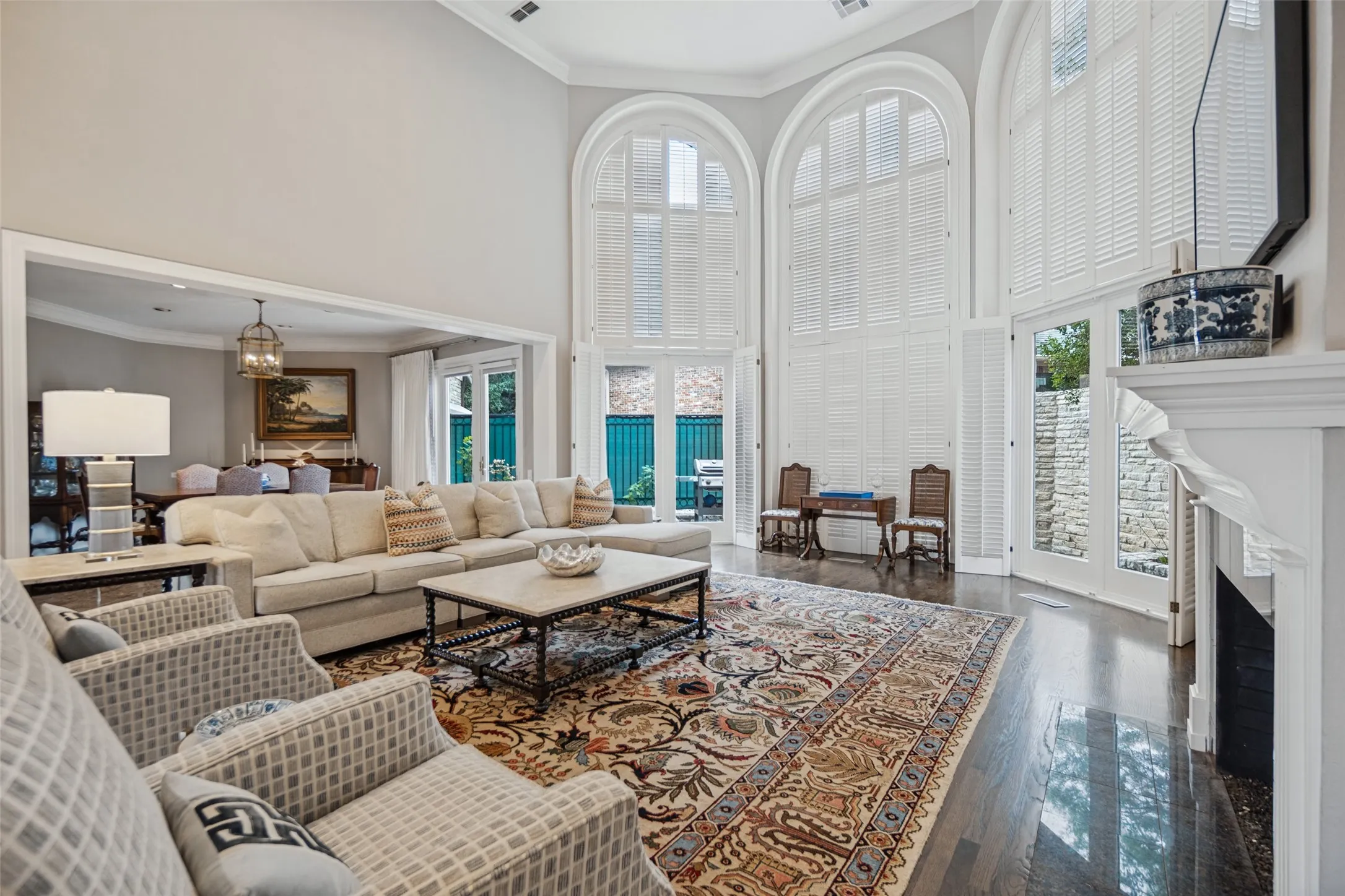 Soaring ceilings, hardwood flooring, fireplace, and arched windows with plantation shutters