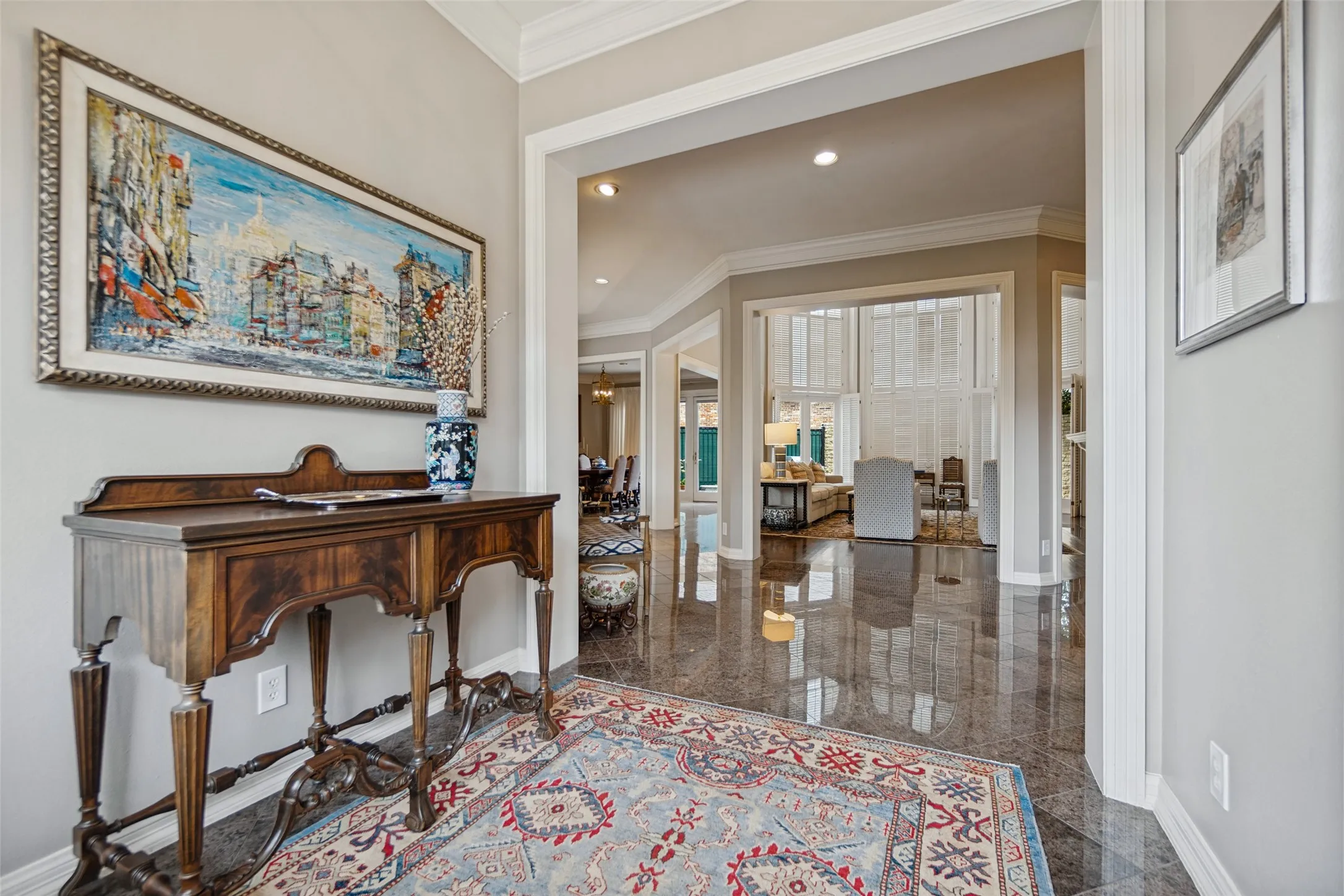 Polished stone tile flooring, high ceilings with crown molding, and an open entryway with arched doorways
