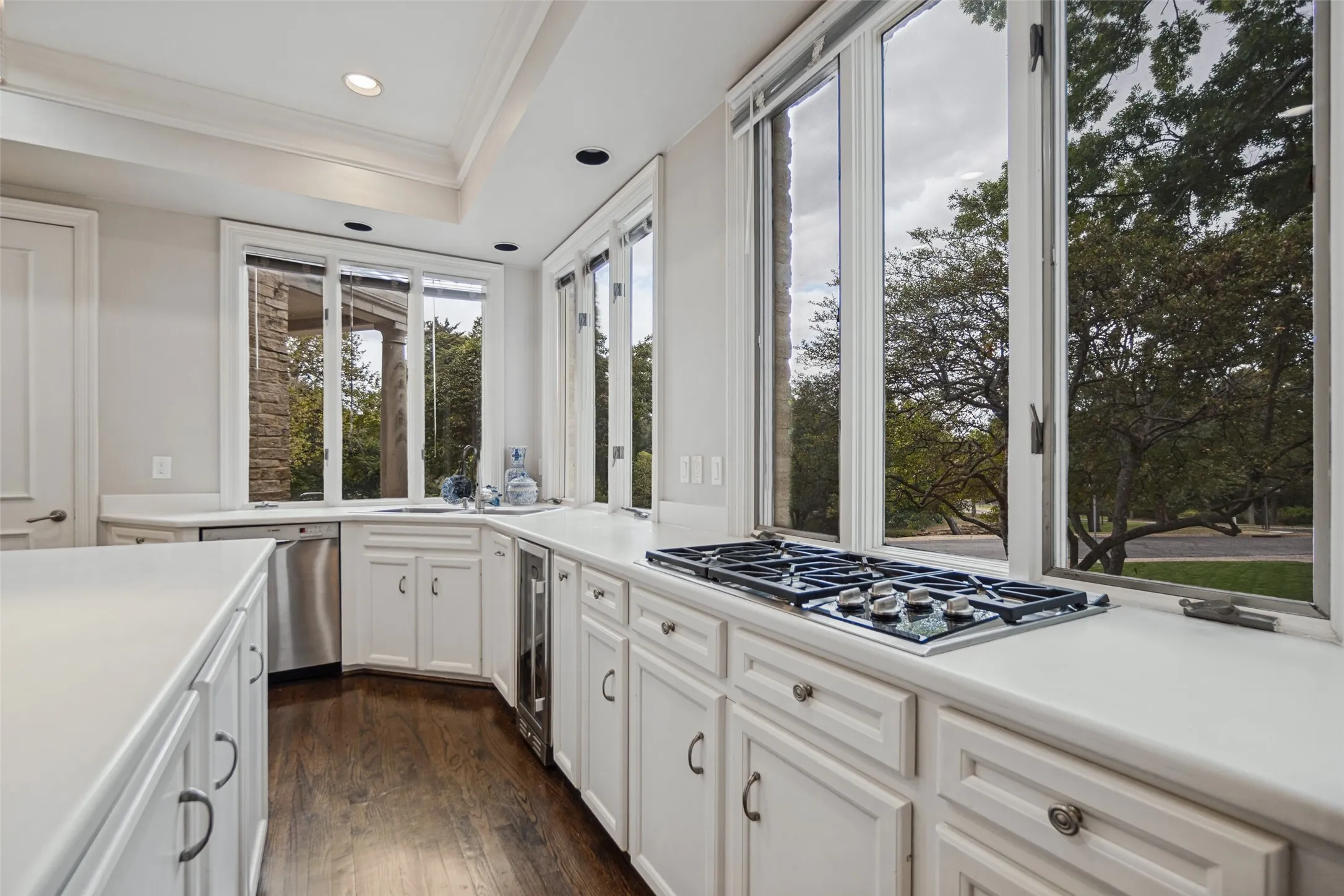 Kitchen featuring white cabinetry, light-colored countertops, a built-in gas cooktop, stainless steel dishwasher, and wood-finish flooring
