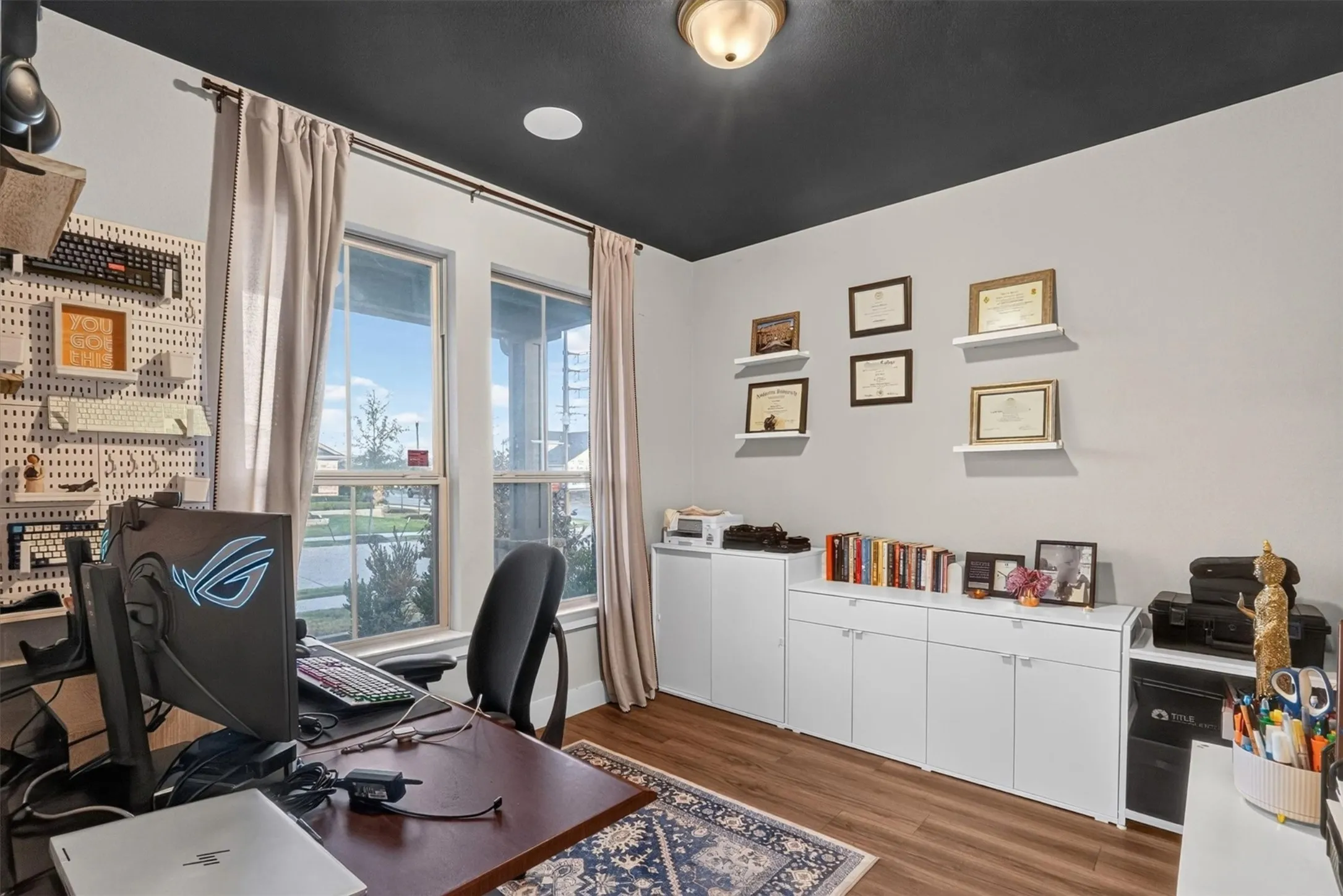 Home office featuring a dark wood desk, ergonomic task chair, and expansive windows with natural light