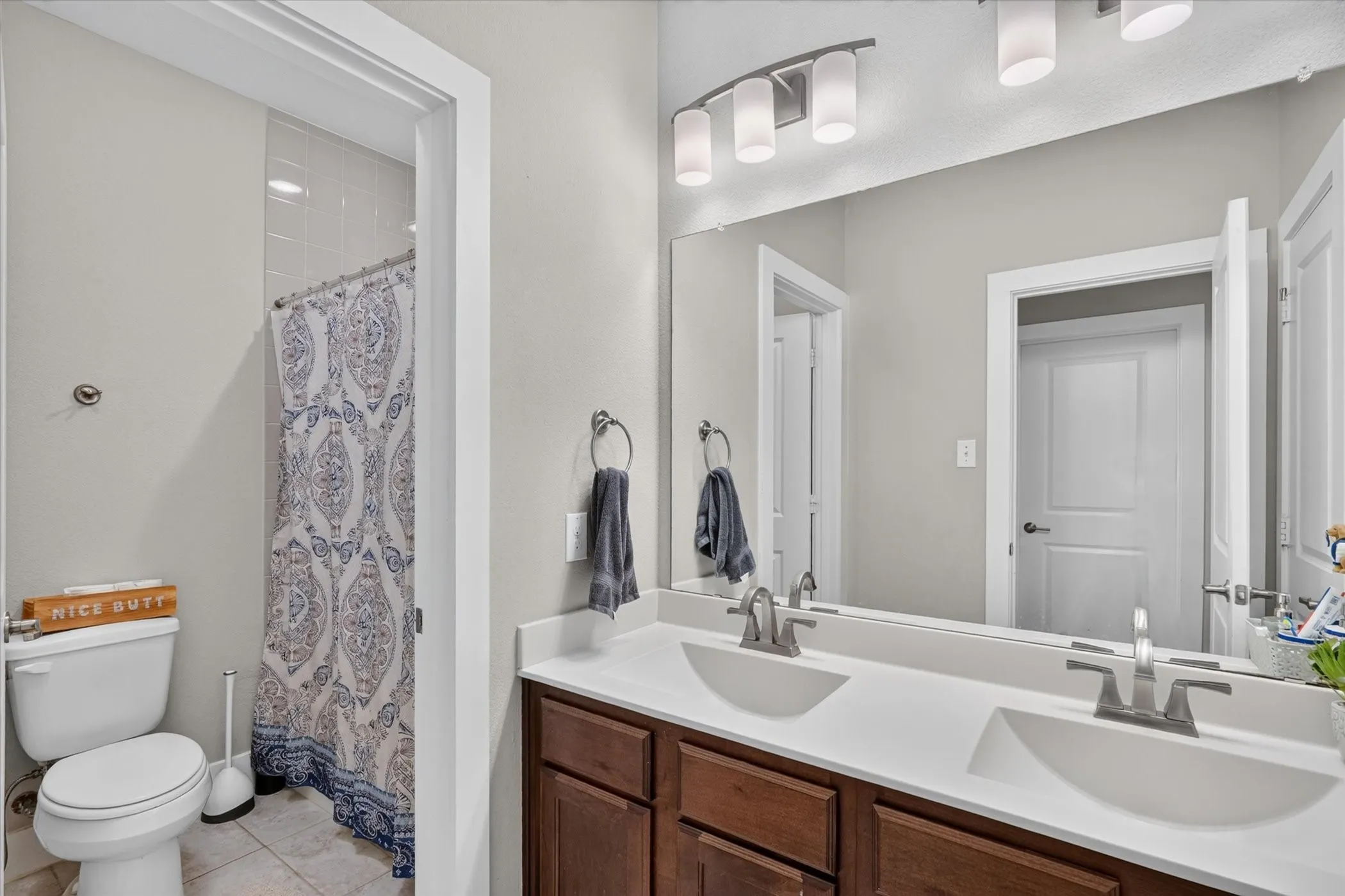 Dual vanity with integrated sinks, brushed nickel fixtures, dark wood-finish cabinetry, and overhead bar lighting