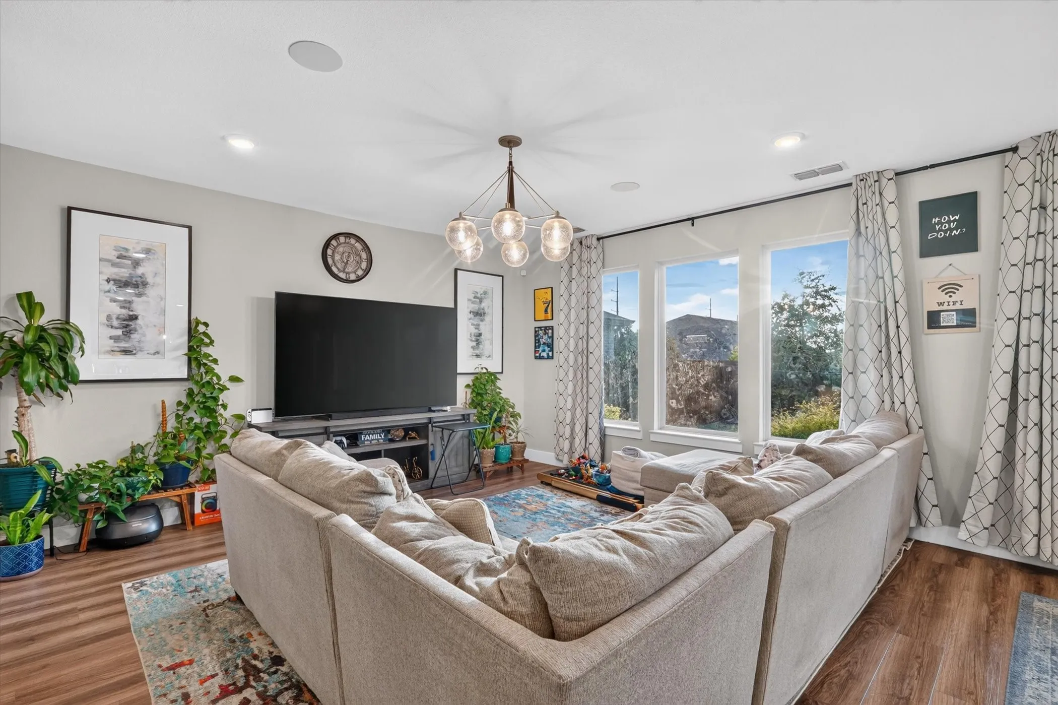 Recessed lighting, wood-finish flooring, and a multi-pane window with dark-finish curtain rods