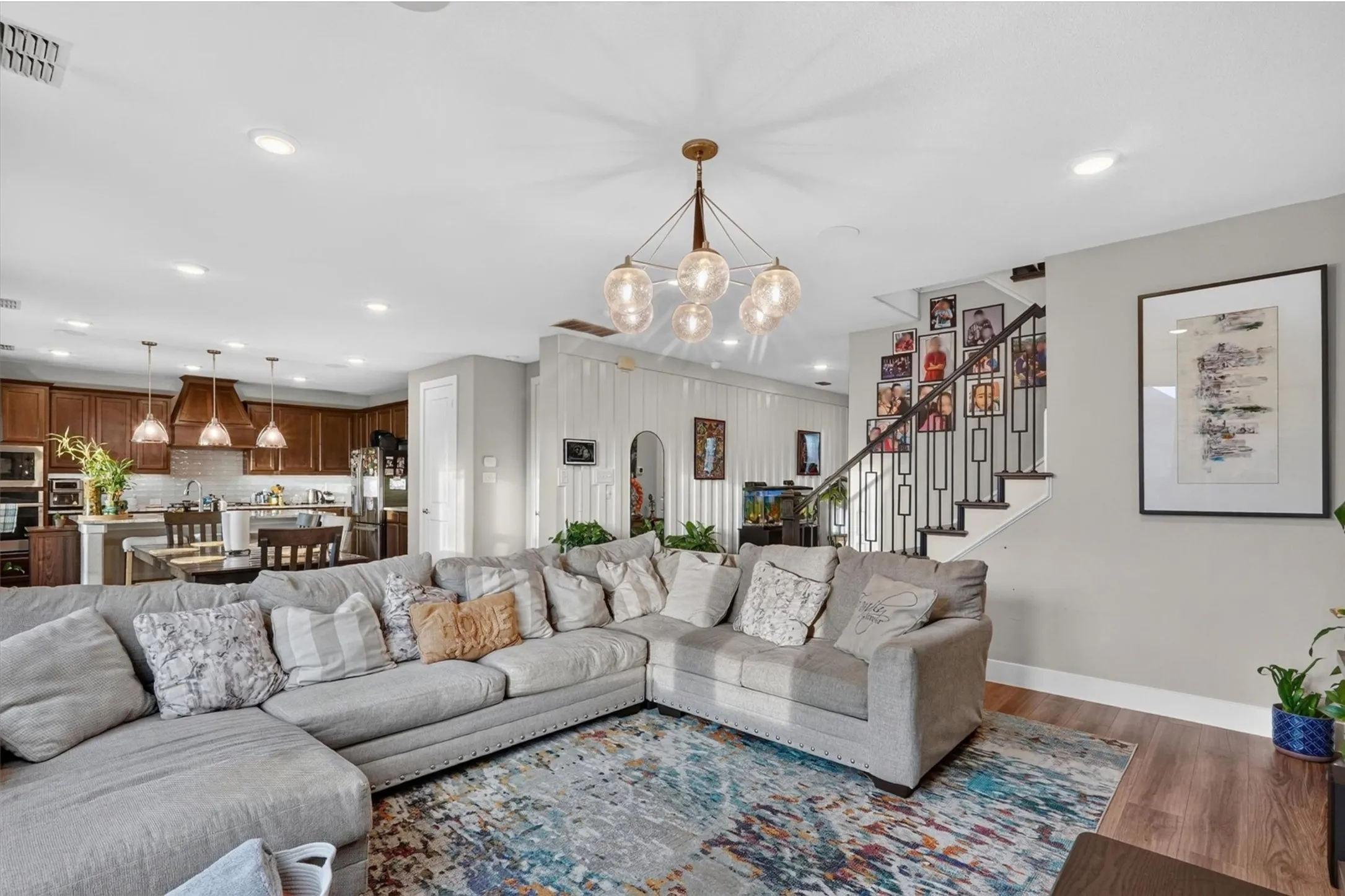 Open-concept living area featuring wood-finish flooring, recessed lighting, and a contemporary chandelier