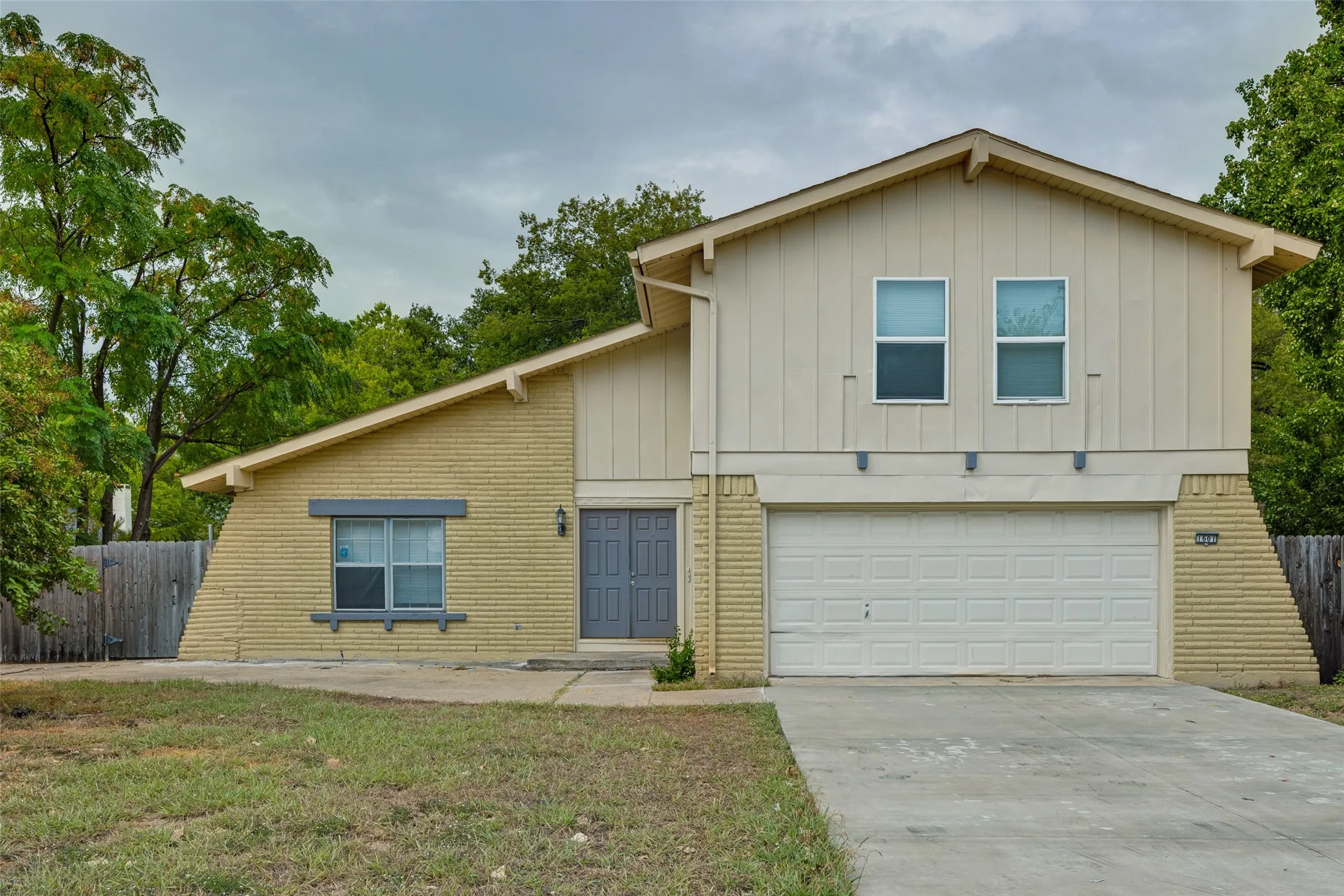 Two-story exterior featuring brick and vertical siding, a two-car garage, and dual entry doors