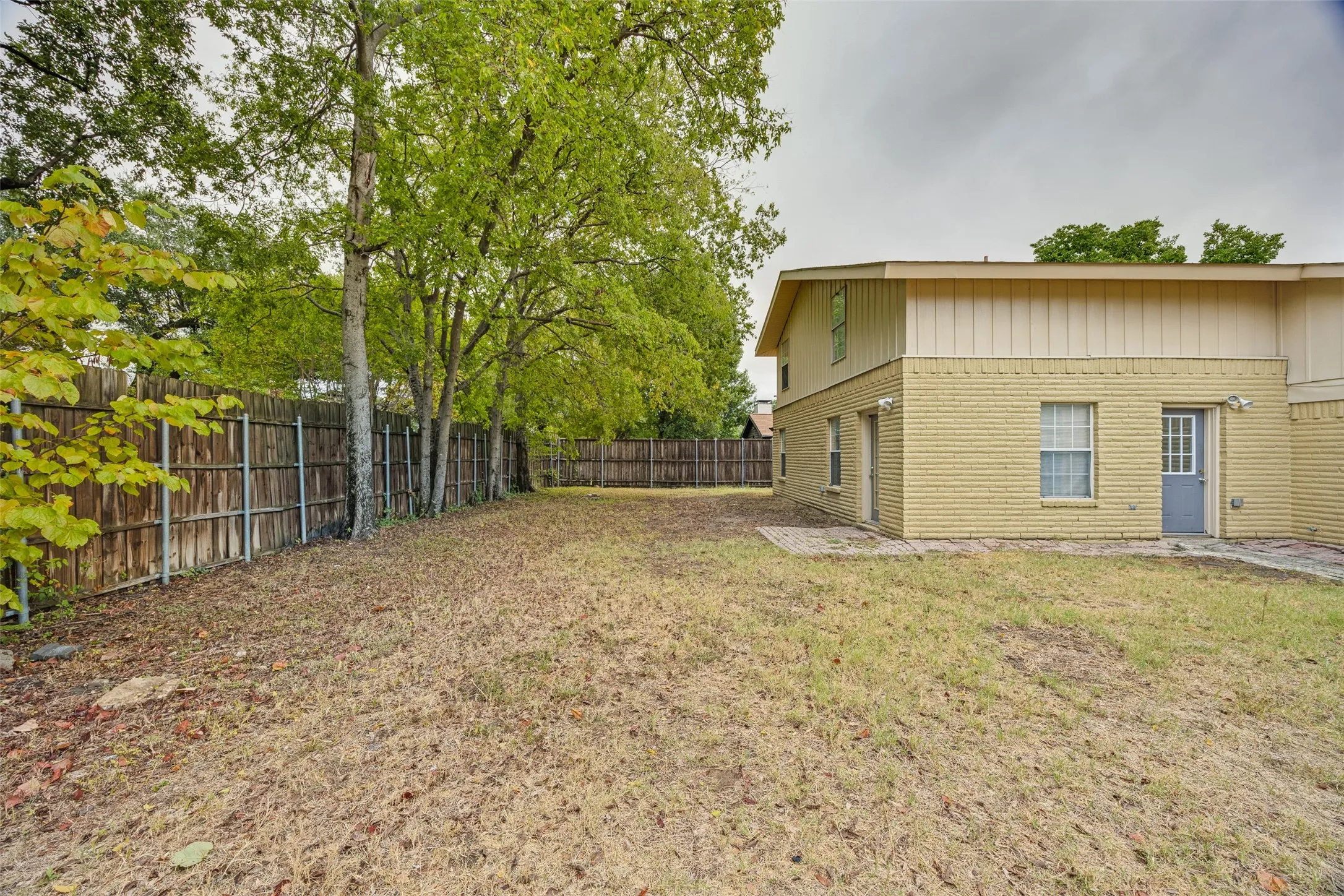 Expansive backyard with a wood privacy fence and mature trees