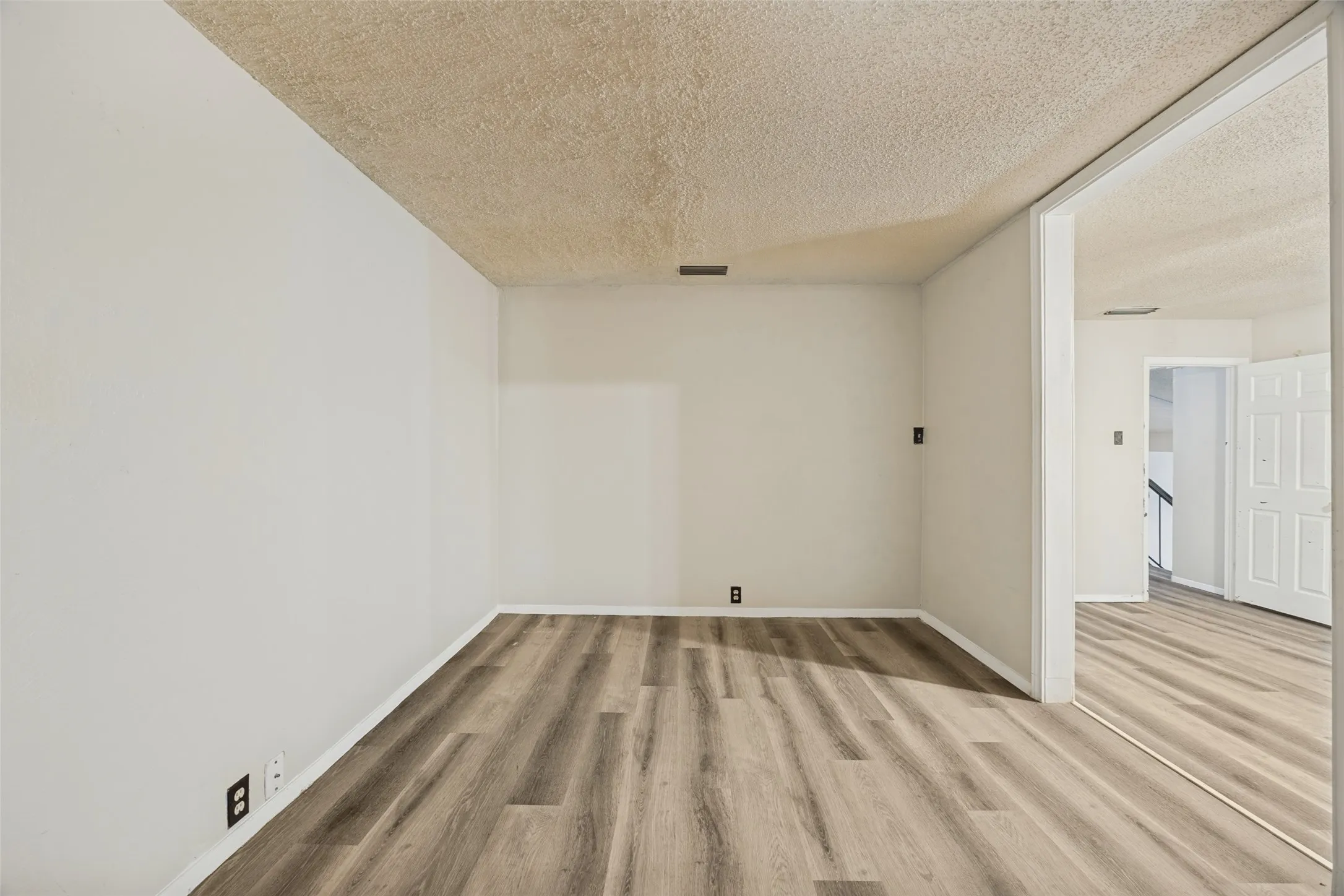 Wood-finish flooring throughout, white wall paint, and overhead recessed lighting