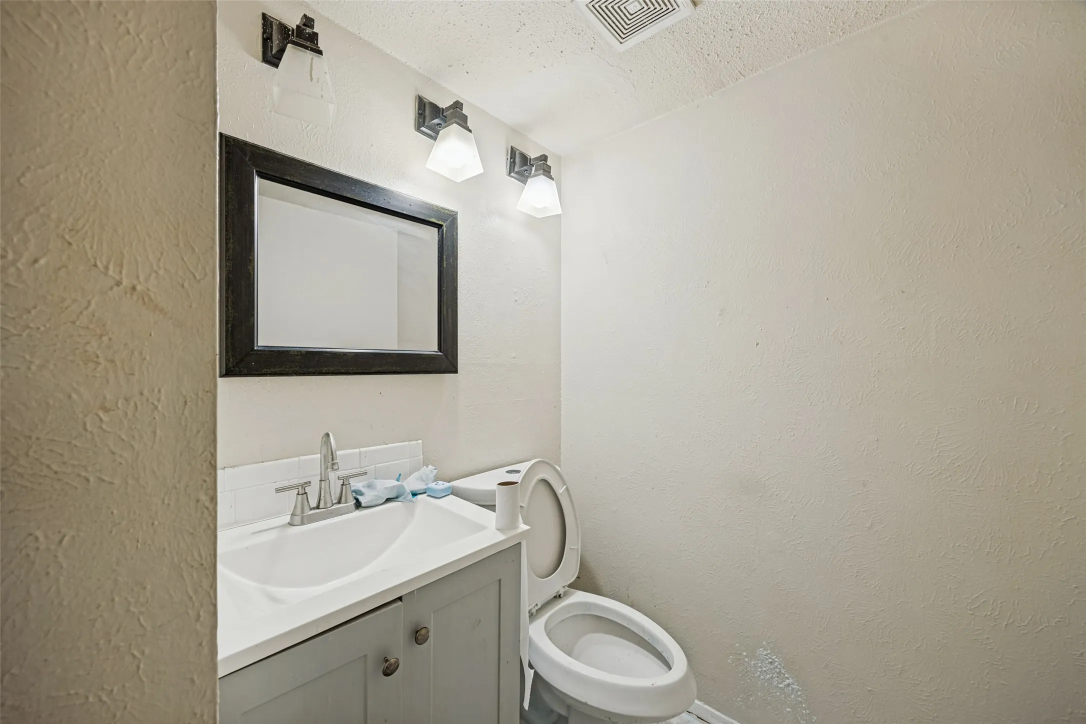 Vanity with a basin sink, chrome faucet, and framed mirror