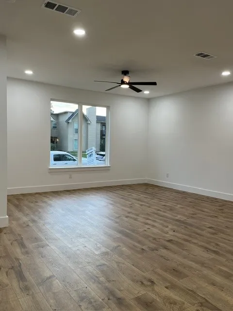 Wood-finish flooring, recessed lighting, ceiling fan, white trim, and a window