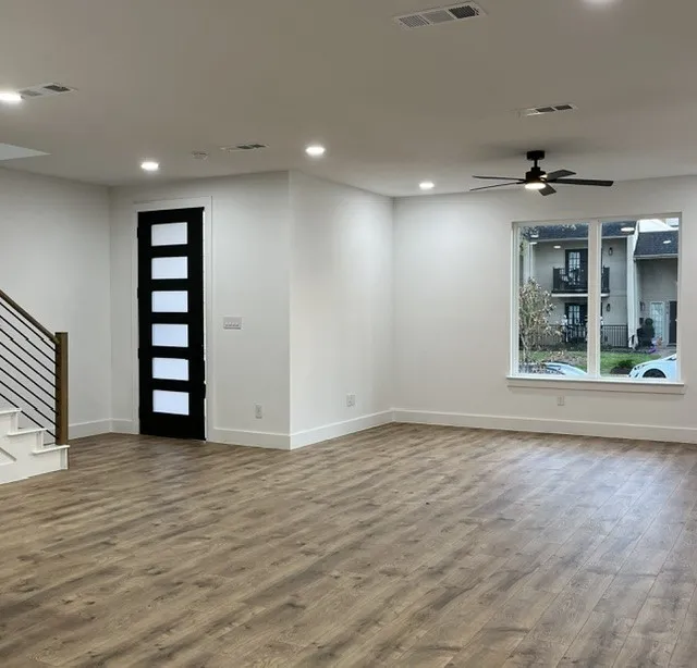 Spacious room with wood-finish flooring, recessed lighting, and a contemporary ceiling fan