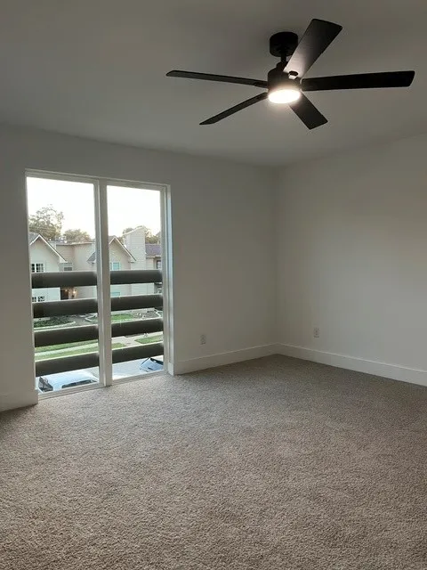 Recessed ceiling light, wall-to-wall carpeting, modern ceiling fan with integrated lighting, white walls, and a sliding glass door