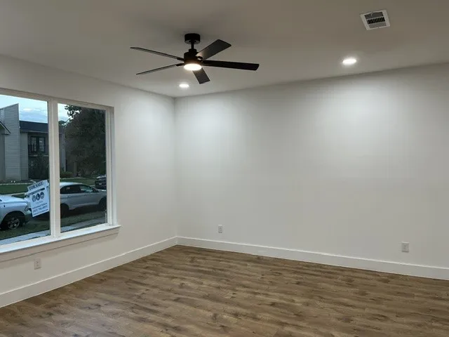 Wood-finish flooring, white walls, and a large window