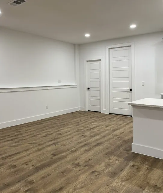 Wood-finish flooring, recessed lighting, white panel doors, and a partial countertop with light-toned surface
