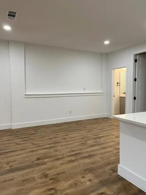 Recessed lighting, wood-finish flooring, white walls, white trim, and a partial white countertop