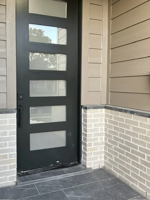 Modern entry door with five rectangular lites, complemented by light-toned brickwork and gray horizontal siding