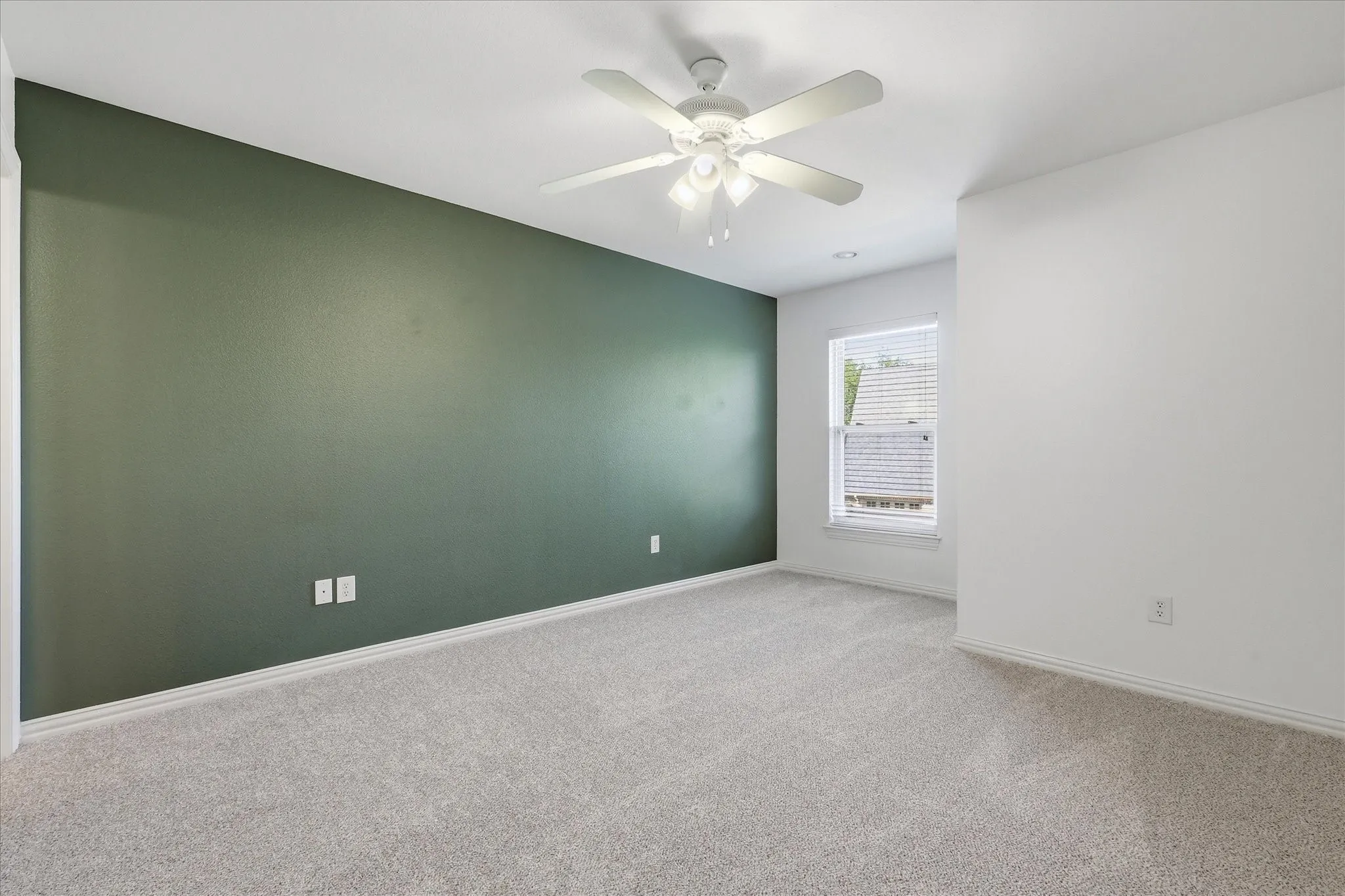 Neutral carpet flooring, dark green accent wall, white ceiling with integrated multi-light ceiling fan, and recessed window