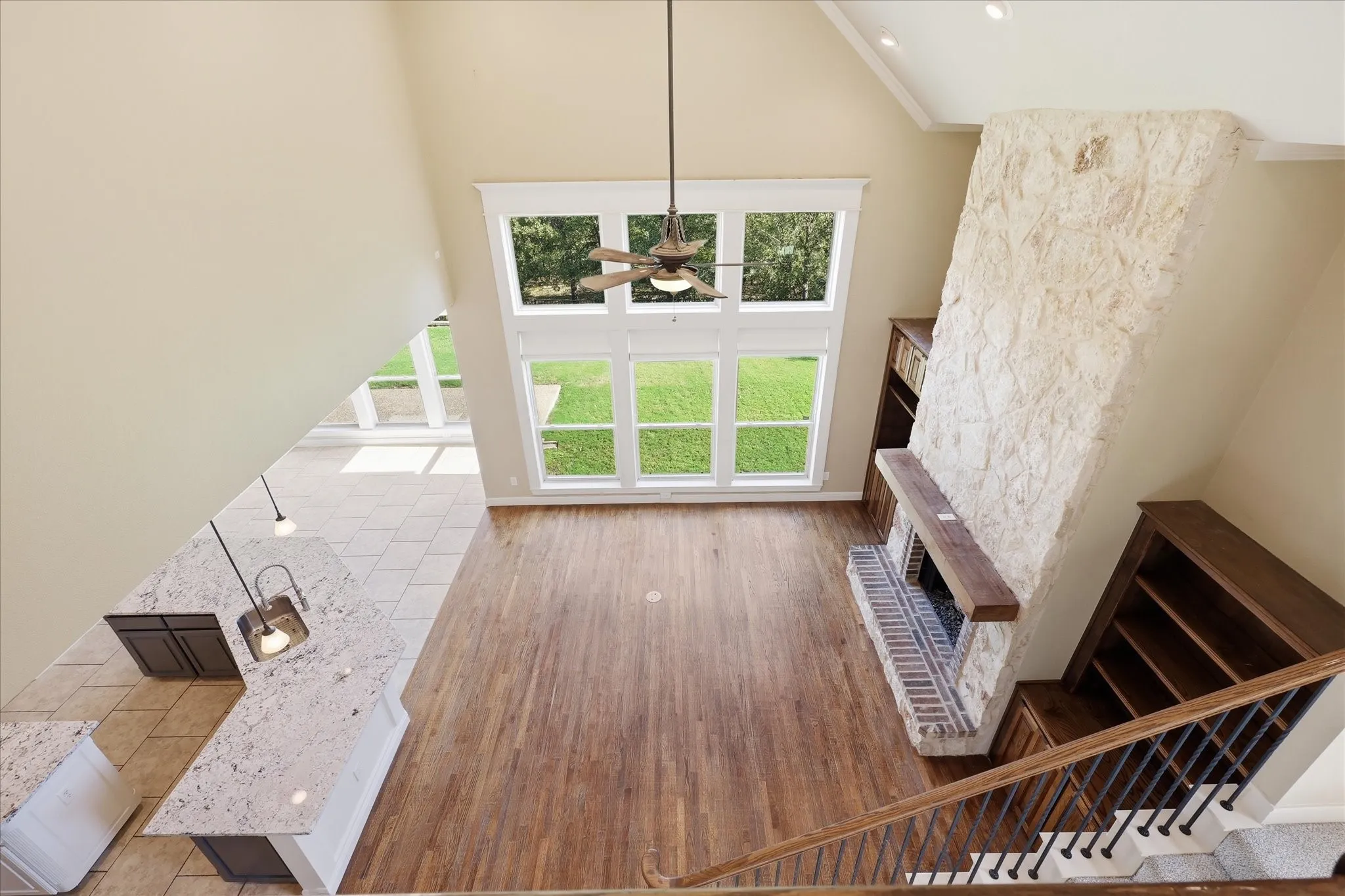 Vaulted ceilings, floor-to-ceiling stone fireplace with a wood mantel, wood-finish flooring, expansive multi-pane windows, and built-in cabinetry