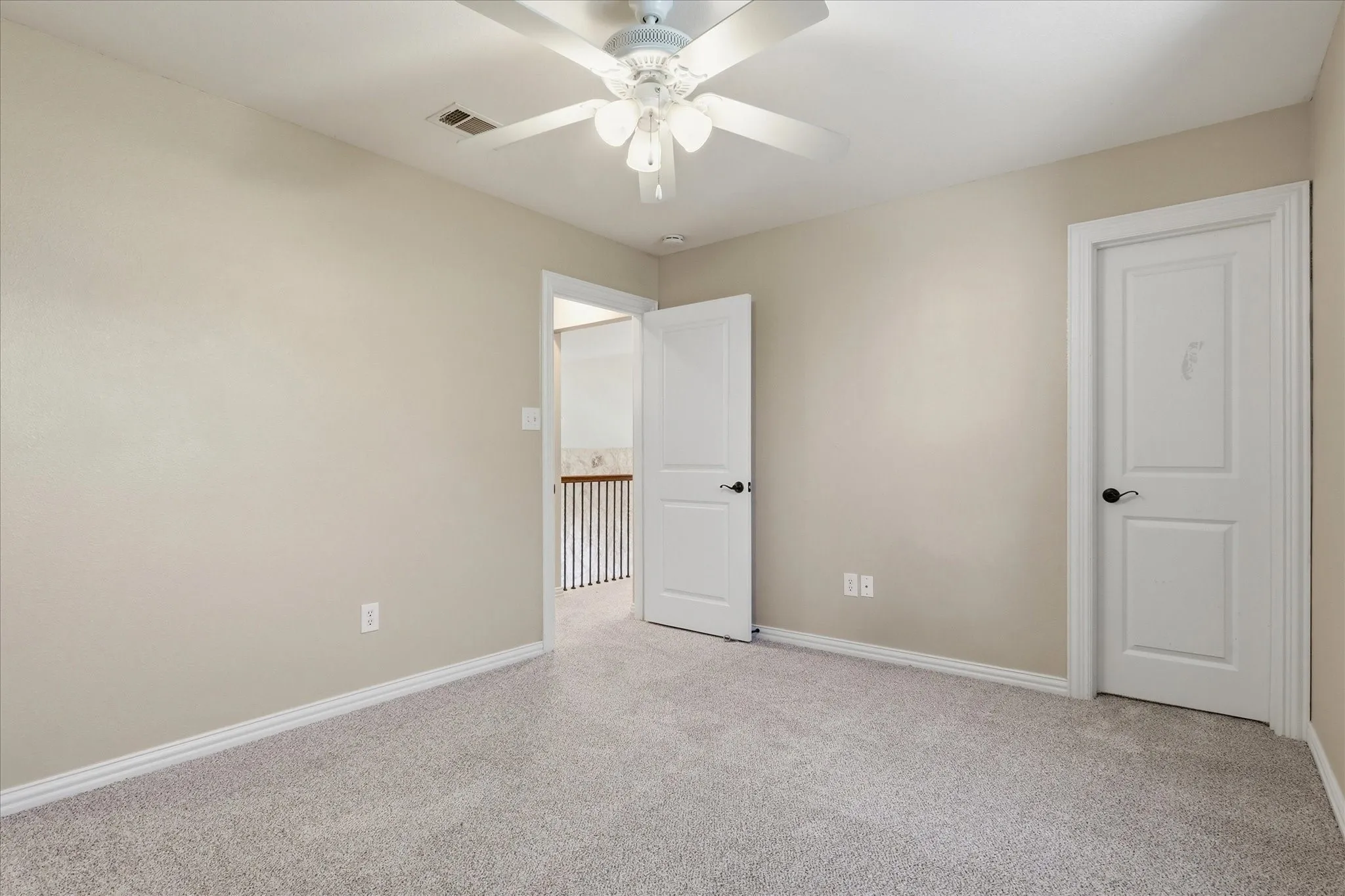 Neutral wall tones, wall-to-wall carpeting, white interior doors with matte black hardware, and a ceiling-mounted light fixture with a fan