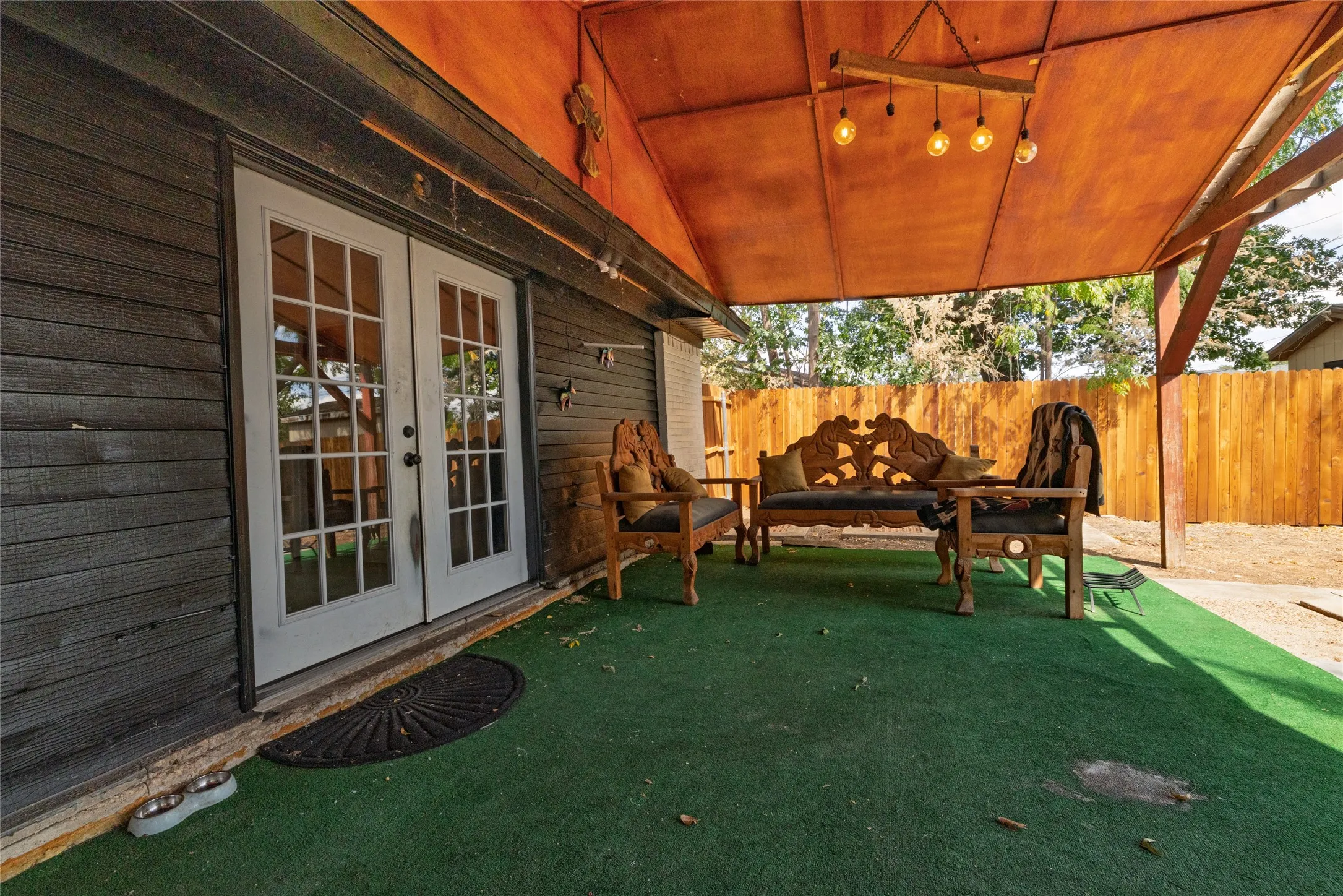 Covered outdoor living space featuring an exposed wood beam ceiling and a built-in chandelier