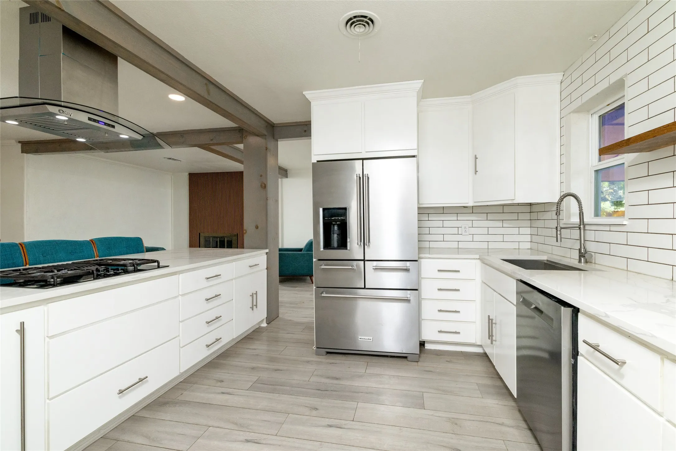 White cabinetry, stainless steel appliances, wood-finish flooring, subway tile backsplash, and recessed lighting