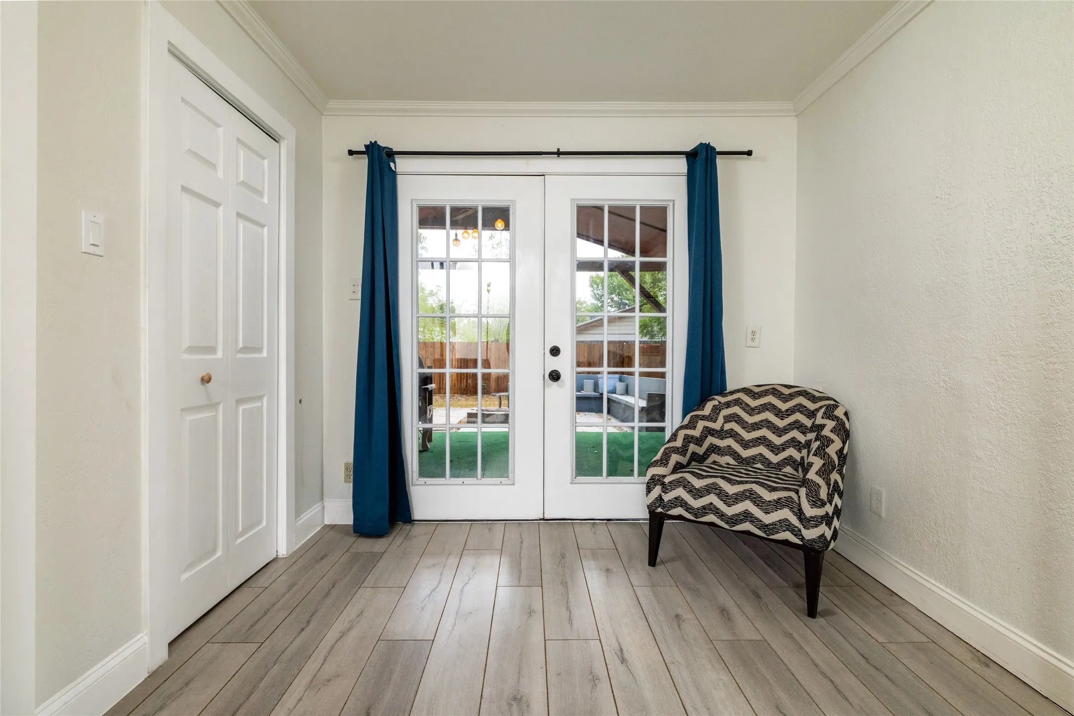 Wood-finish flooring throughout, white paneled doors, and French doors with exterior access