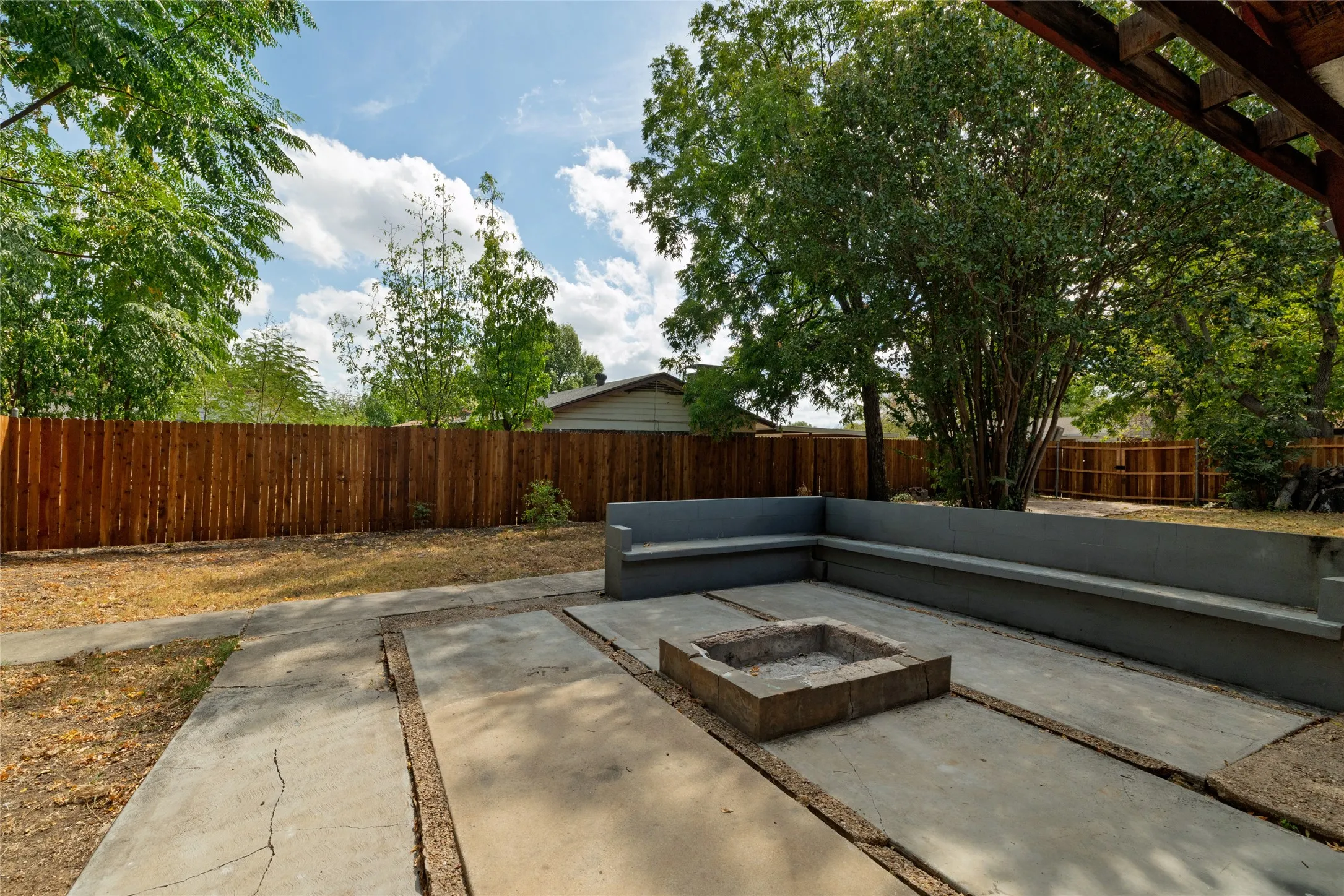 Concrete patio featuring a built-in fire pit and integrated perimeter seating