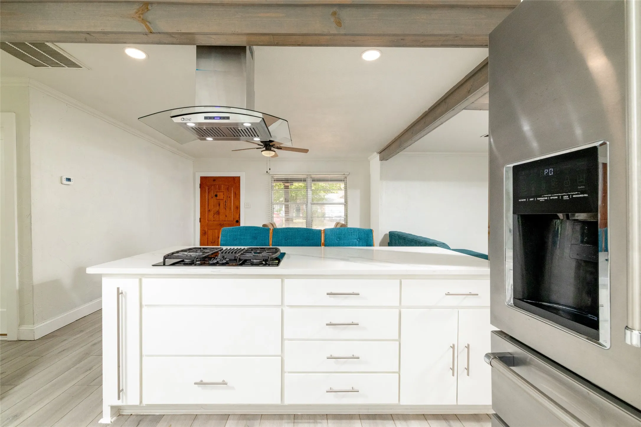 Kitchen island featuring a built-in gas cooktop, white cabinetry with brushed nickel hardware, and a solid surface countertop