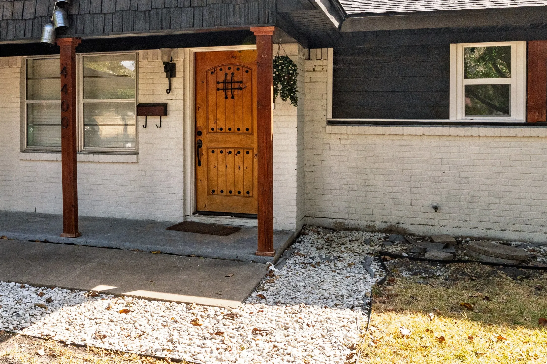 Exterior entry with white painted brick siding, wood plank columns, and a solid wood front door