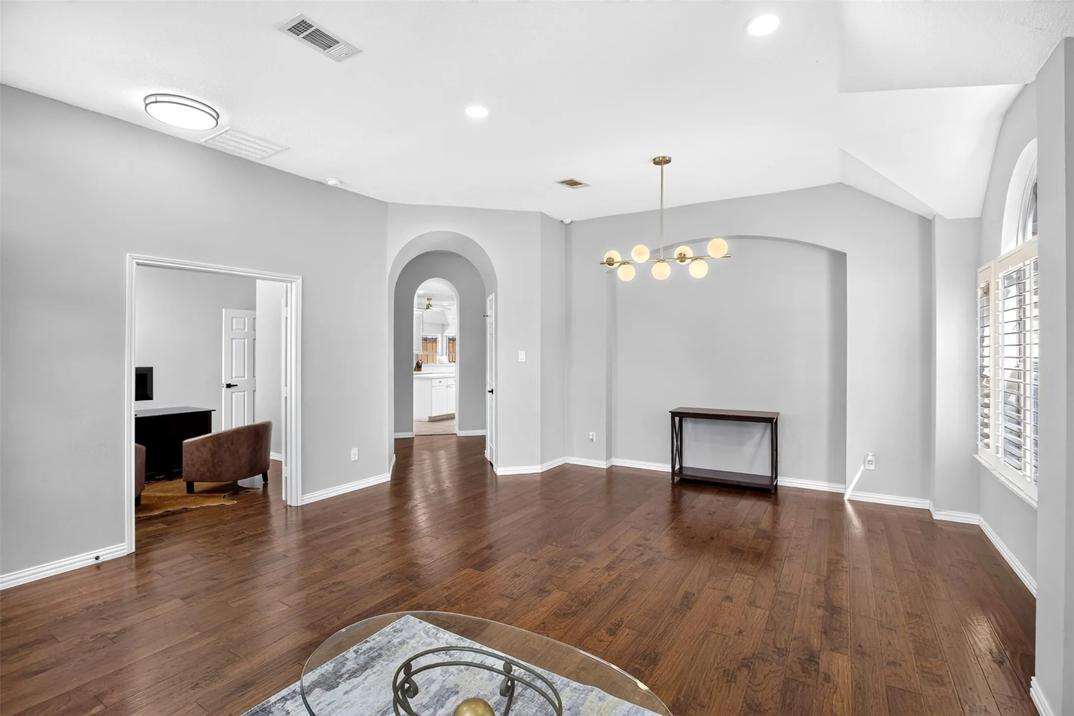 Wood-finish flooring, recessed lighting, vaulted ceiling, arched doorway, and plantation shutters
