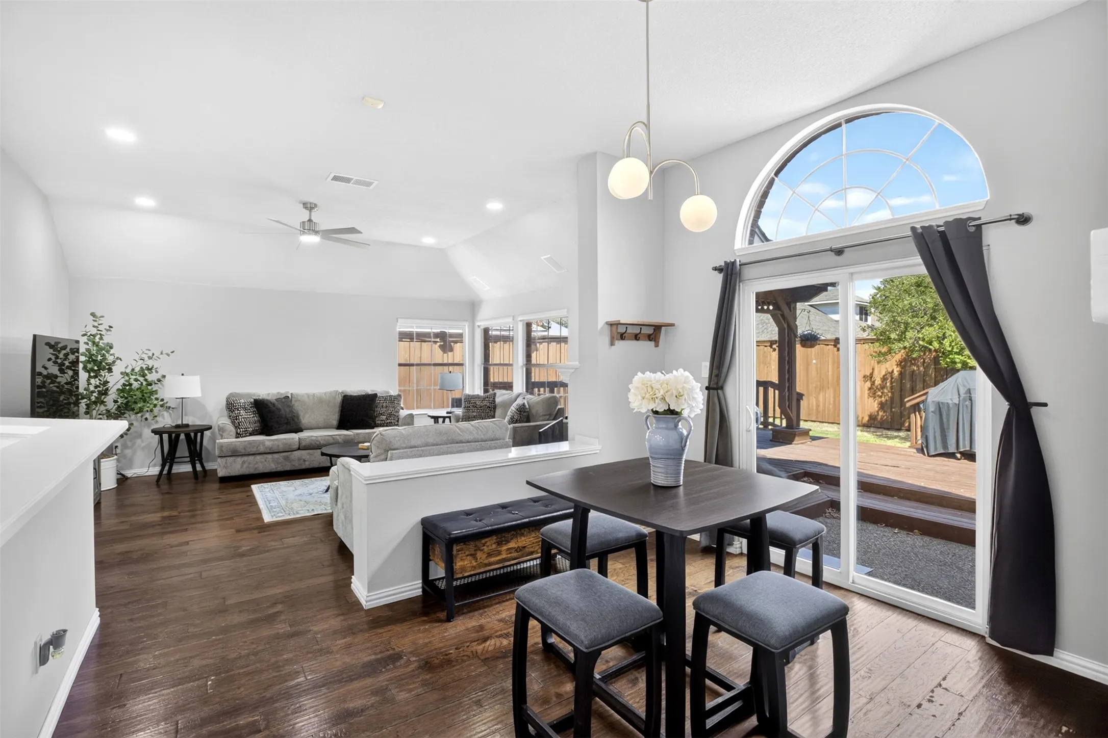 Vaulted ceilings, dark wood-finish flooring, recessed lighting, and a sliding glass door leading to a wood deck