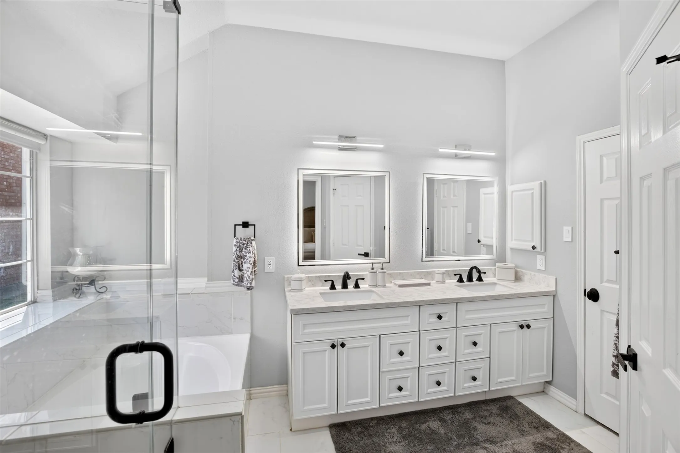 Dual vanity with white cabinetry, matte black hardware, and light-toned countertops